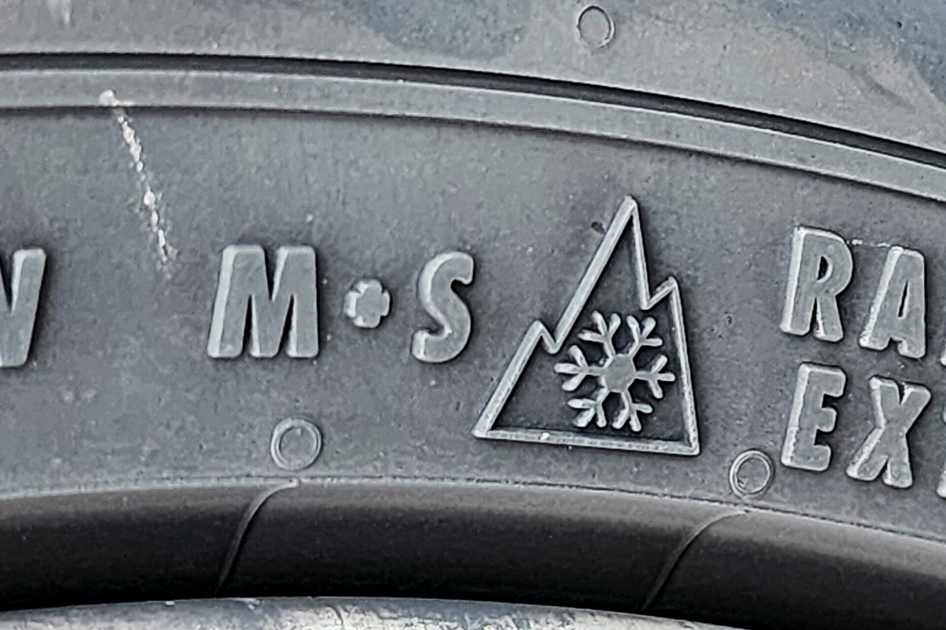 The three-peak mountain snowflake symbol and M+S marking moulded into a tyre sidewall