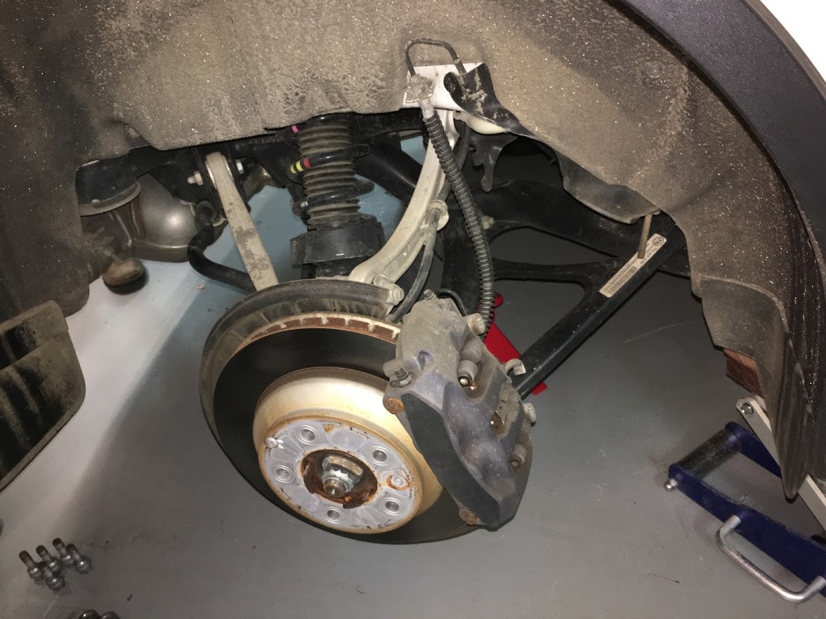A car brake disc and caliper seen with the wheel removed