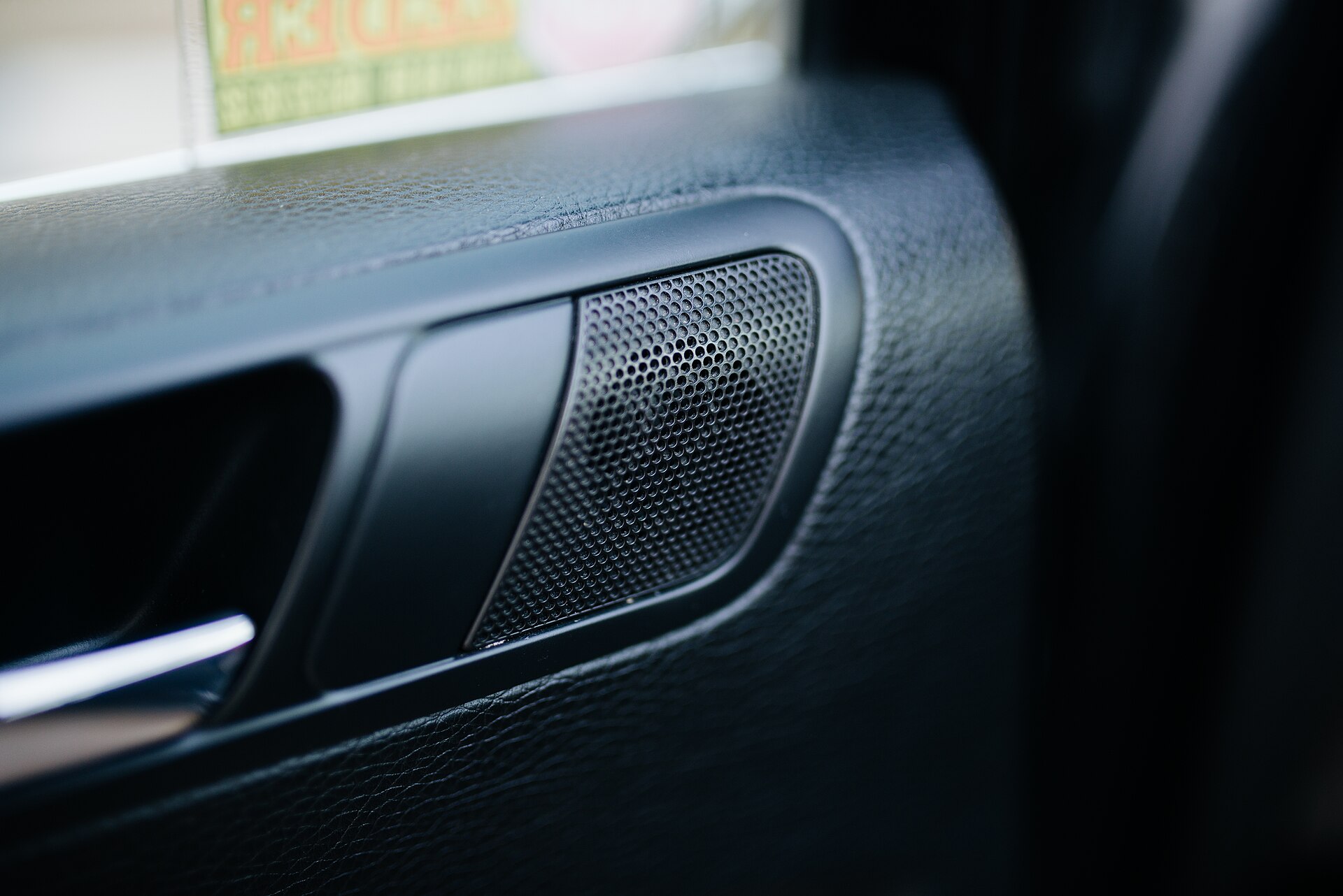 Close-up of a speaker grille set into a car's interior door panel