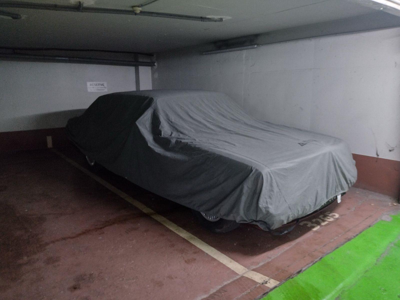 A car under a grey fitted cover in an underground car park