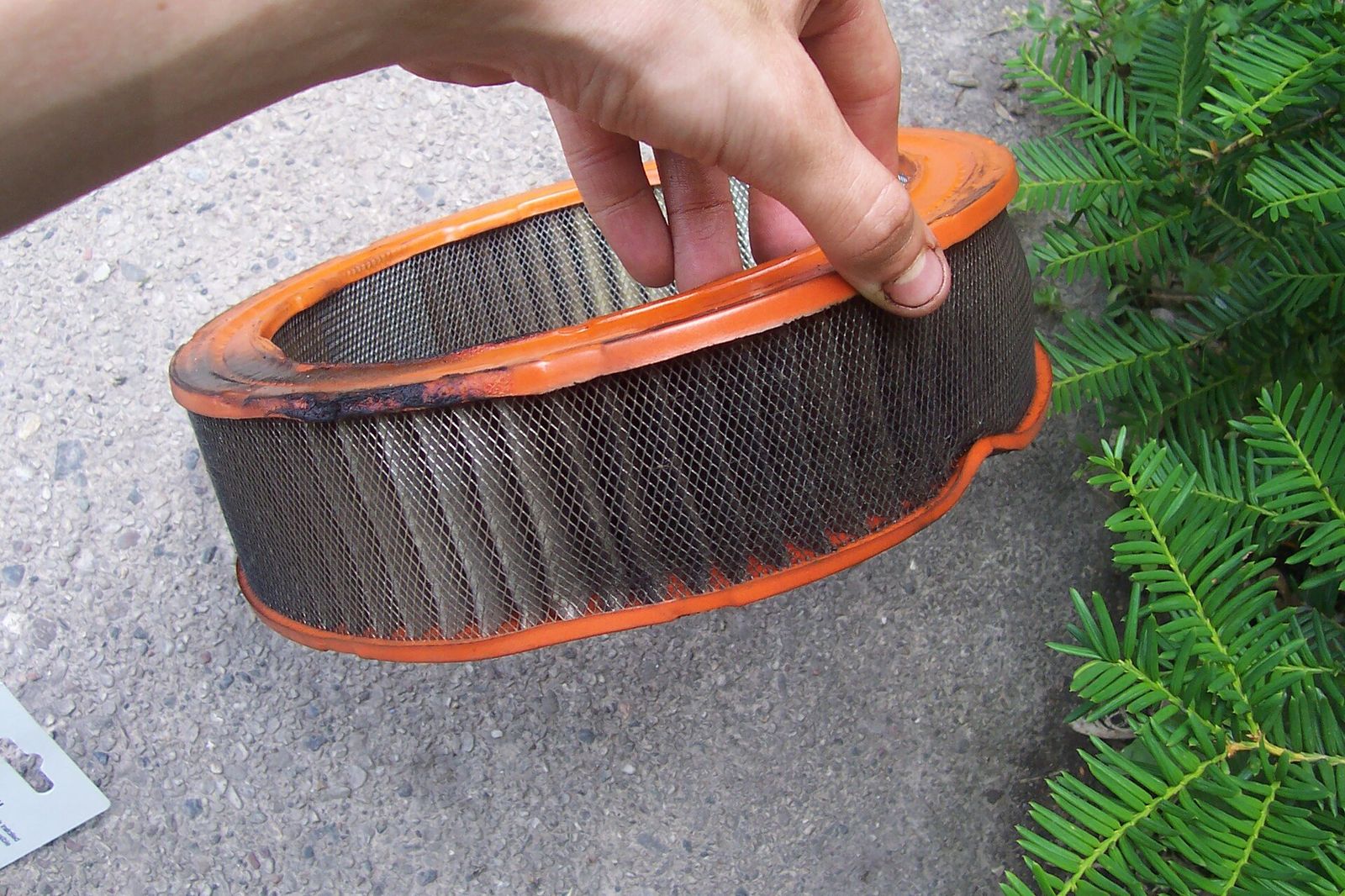 A dirty panel engine air filter, its pleated paper darkened by trapped dust