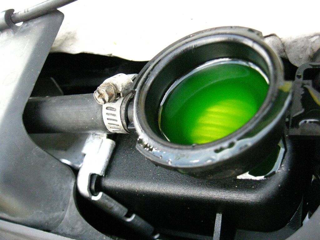 Bright green coolant visible through the open filler neck of a car's cooling system