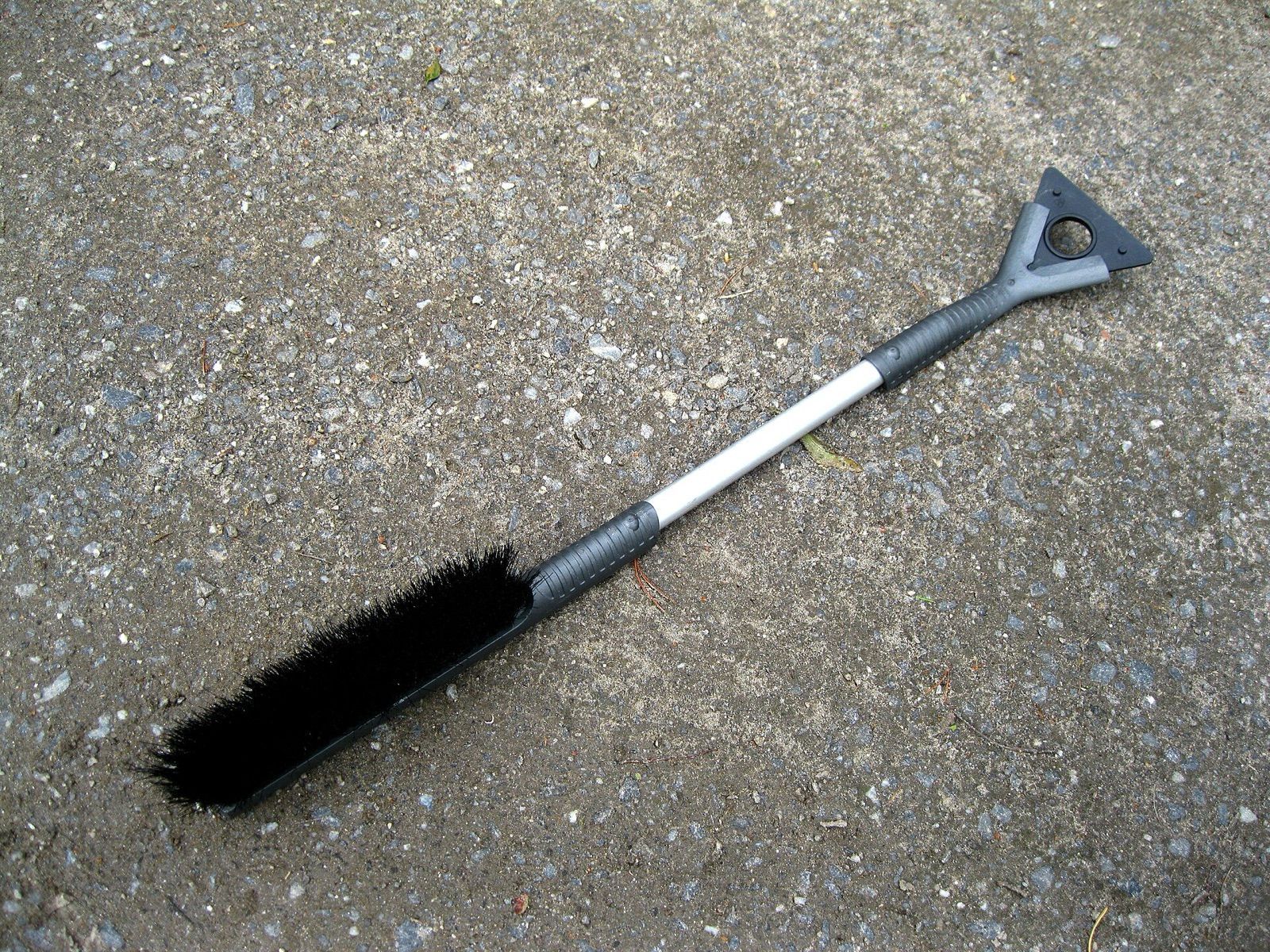 A long-handled snow brush with an ice scraper head