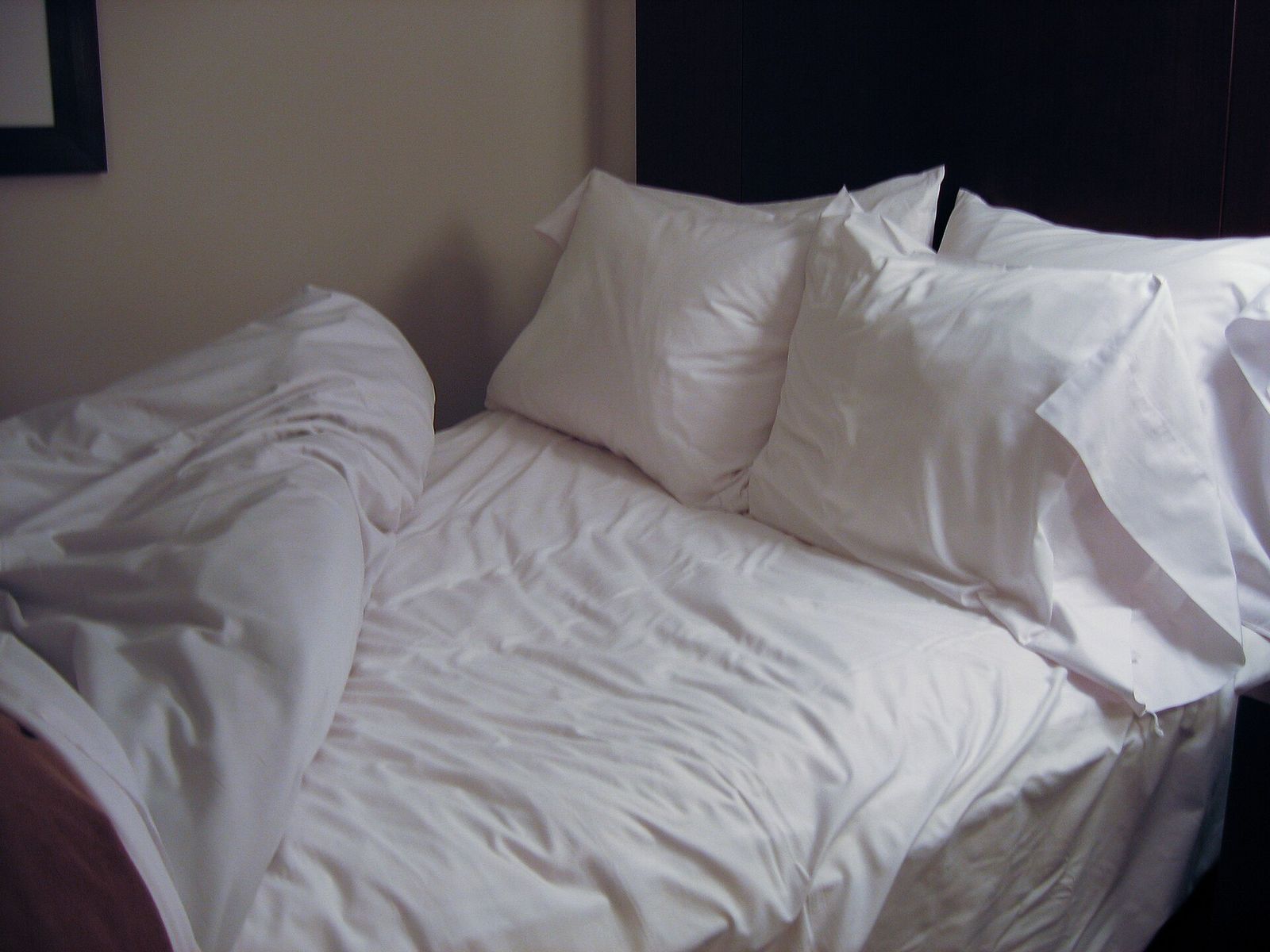 Bed made up with white sheets, a white duvet and several pillows