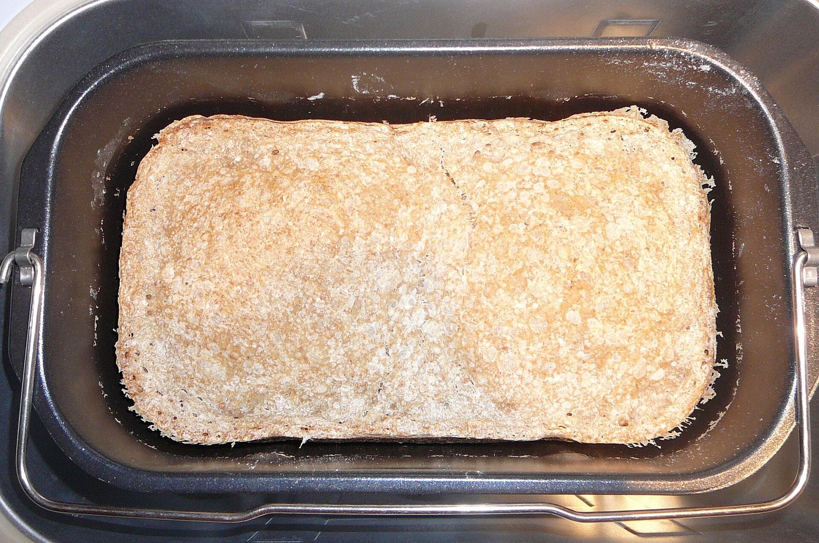 A freshly baked loaf seen from above in the non-stick pan of a bread maker