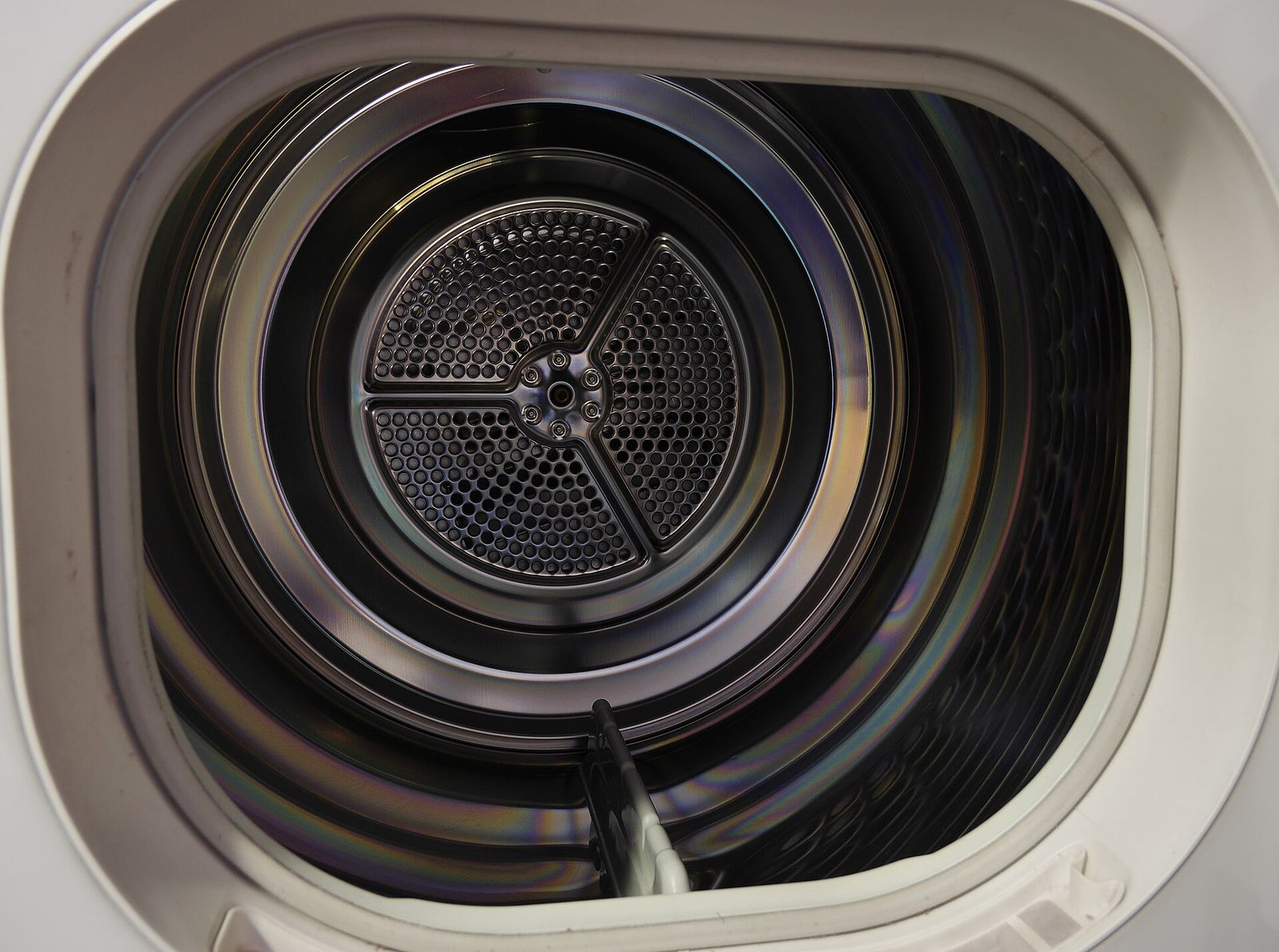 The perforated stainless-steel drum seen through the open door of a tumble dryer