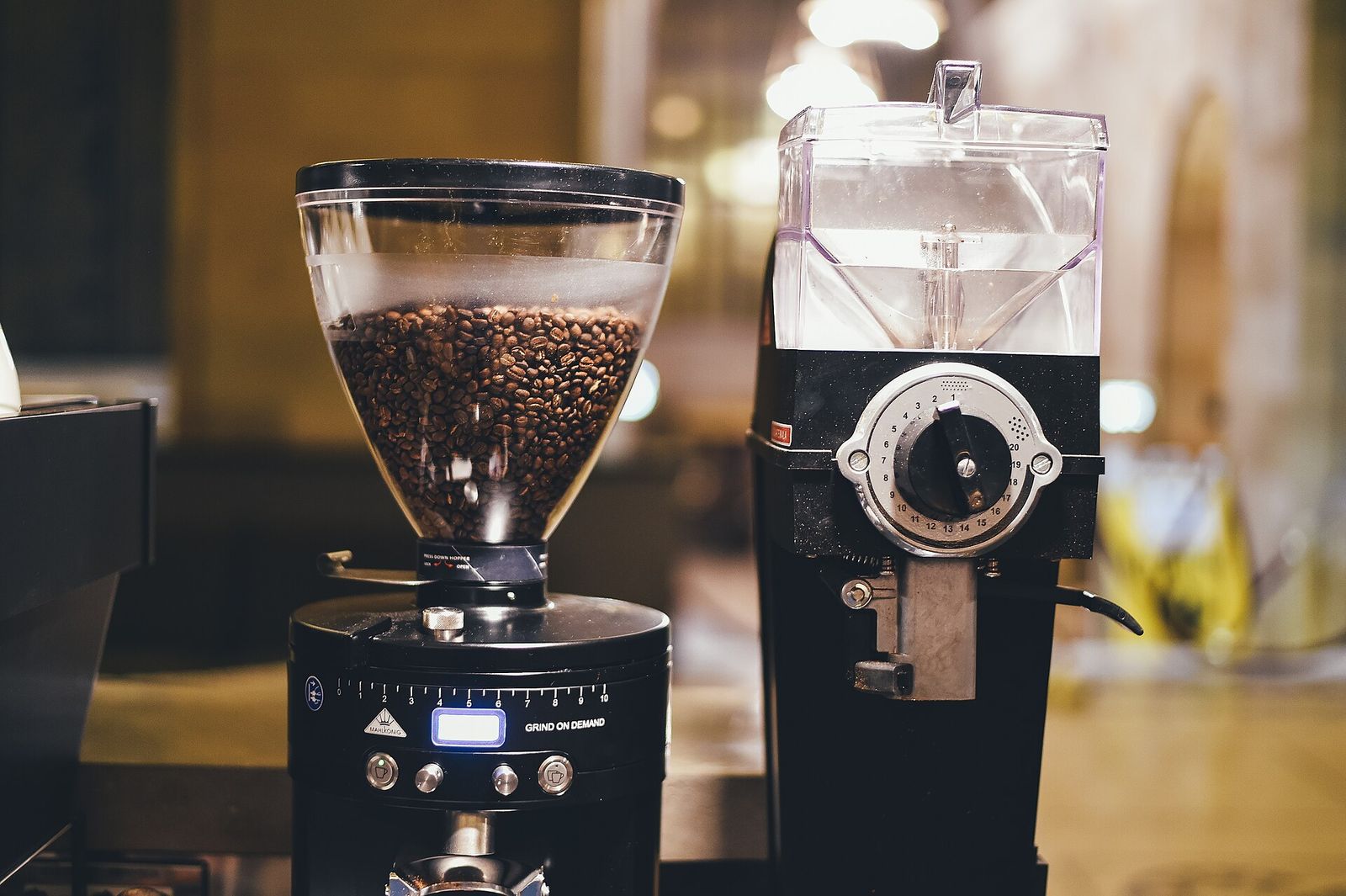 Two burr coffee grinders with hoppers full of beans