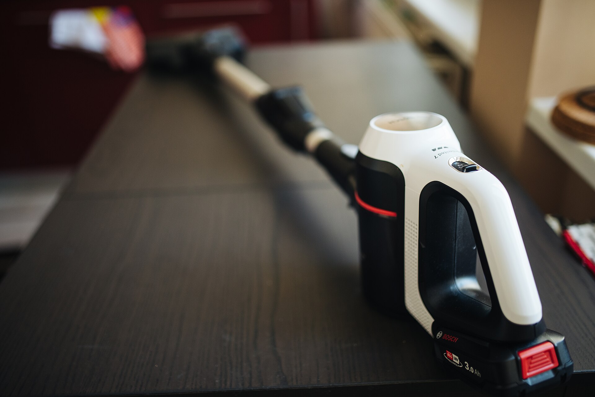 Cordless stick vacuum with its battery pack, resting on a kitchen table