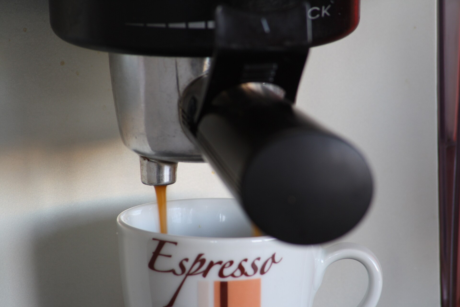 Espresso pouring from a portafilter into a small cup