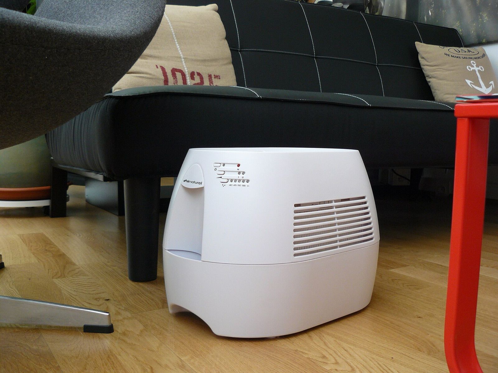 Evaporative humidifier on a wooden floor beside a sofa