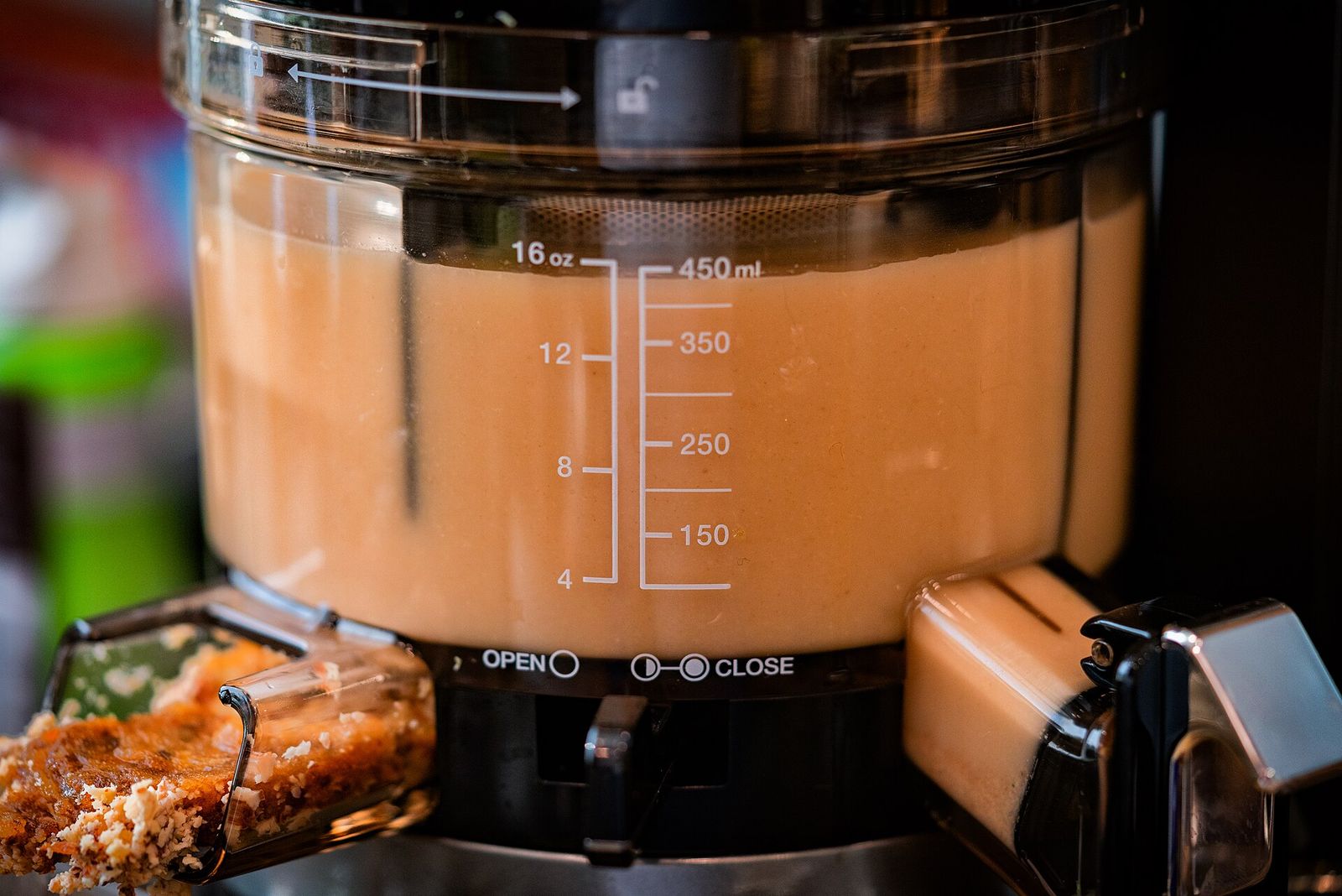 The chamber of a vertical slow juicer, filled to the measuring marks, with pressed pulp at the outlet