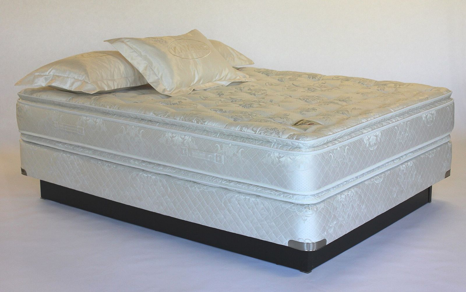 Pillow-top mattress on a box spring against a plain white background