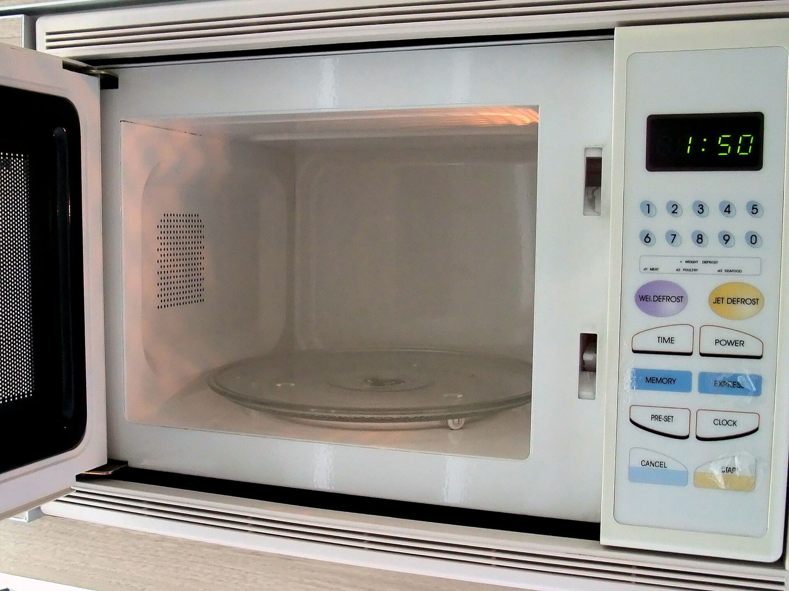 A built-in microwave oven with its door open, showing the glass turntable and keypad