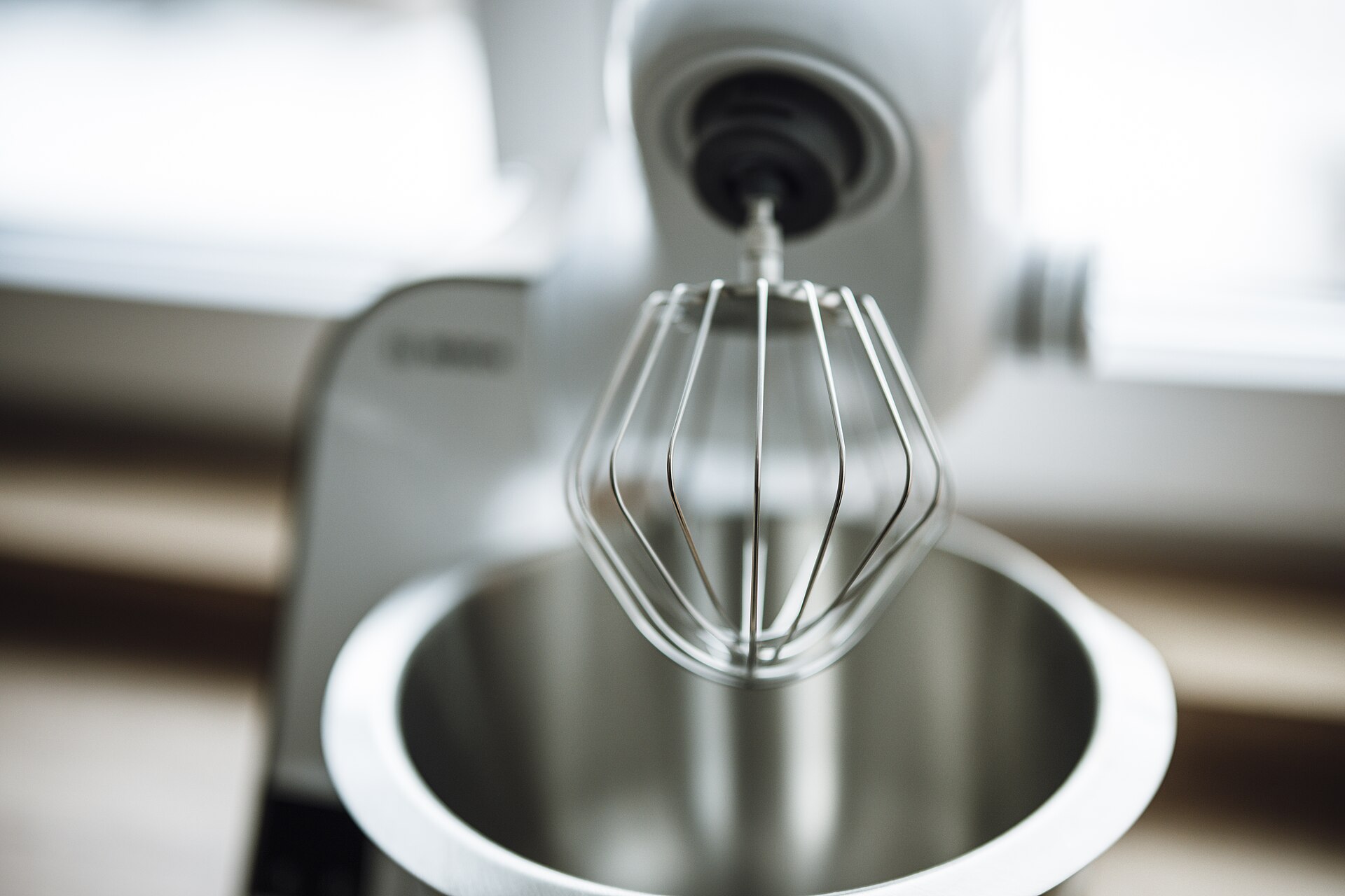 Stand mixer with a balloon whisk above its stainless steel bowl
