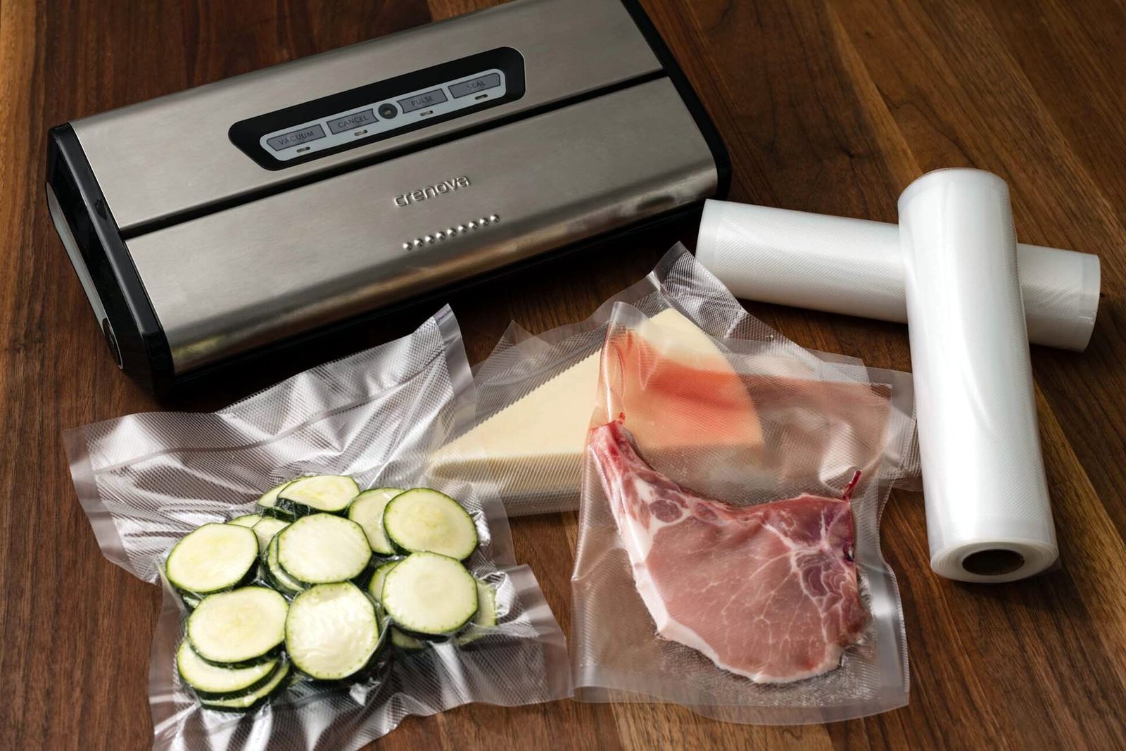 Countertop vacuum sealer beside vacuum-sealed courgette slices, meat and rolls of sealer bag