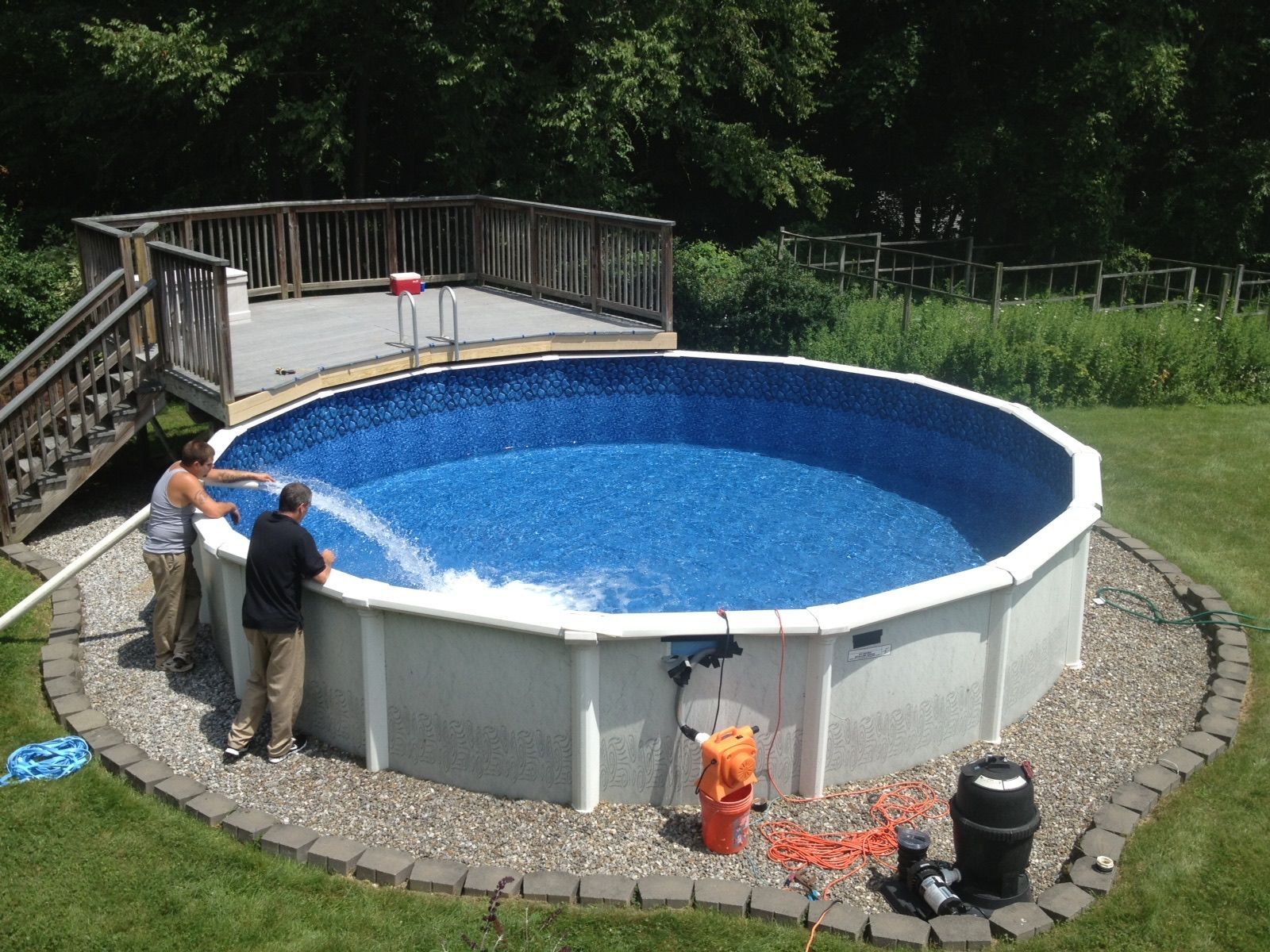 Round above-ground pool being filled, with its pump and sand filter beside the wall
