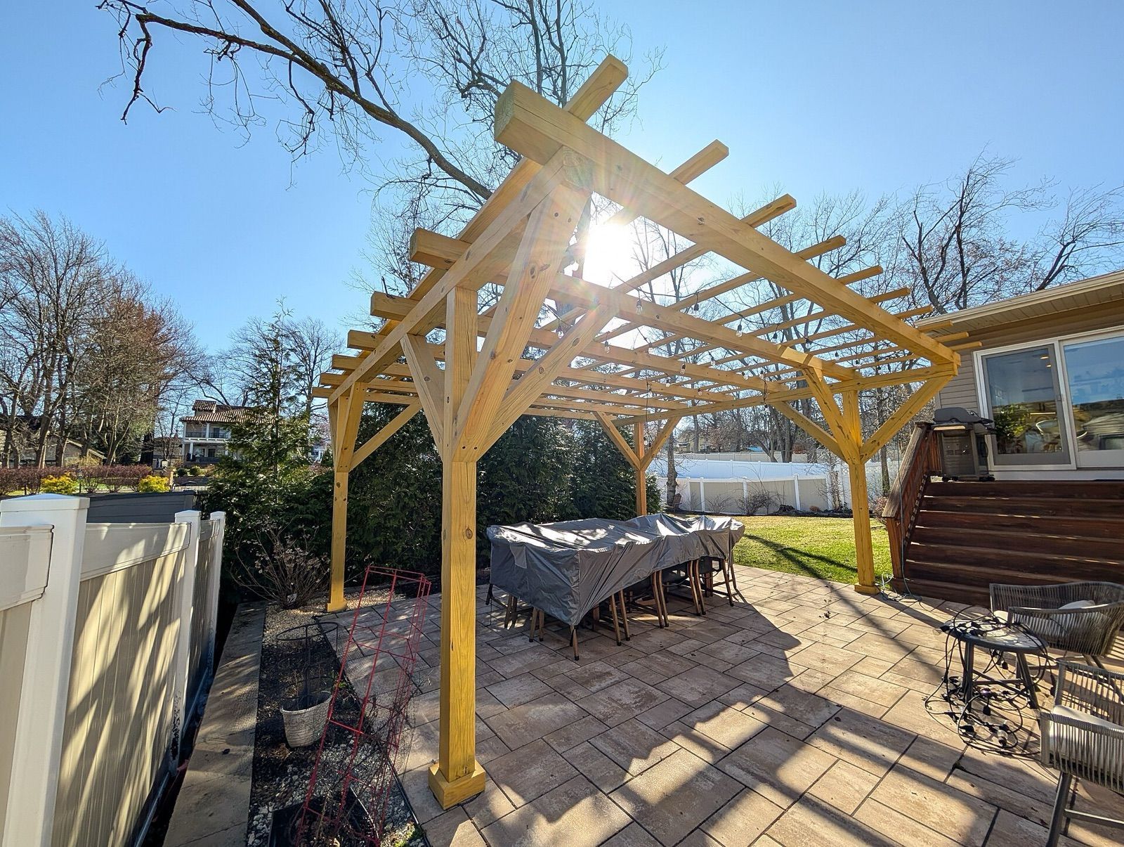 Timber pergola over a paved backyard patio with outdoor furniture