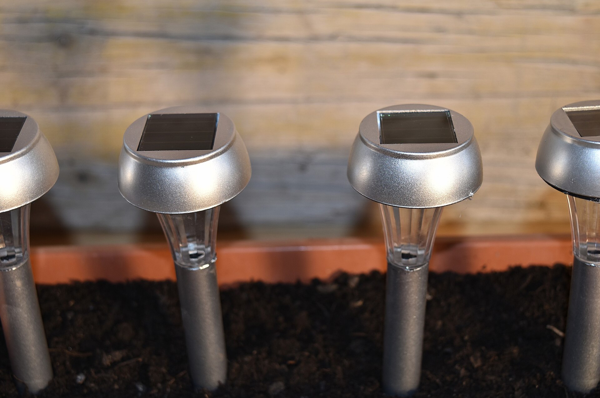 Row of solar-powered garden stake lights with small panels on top