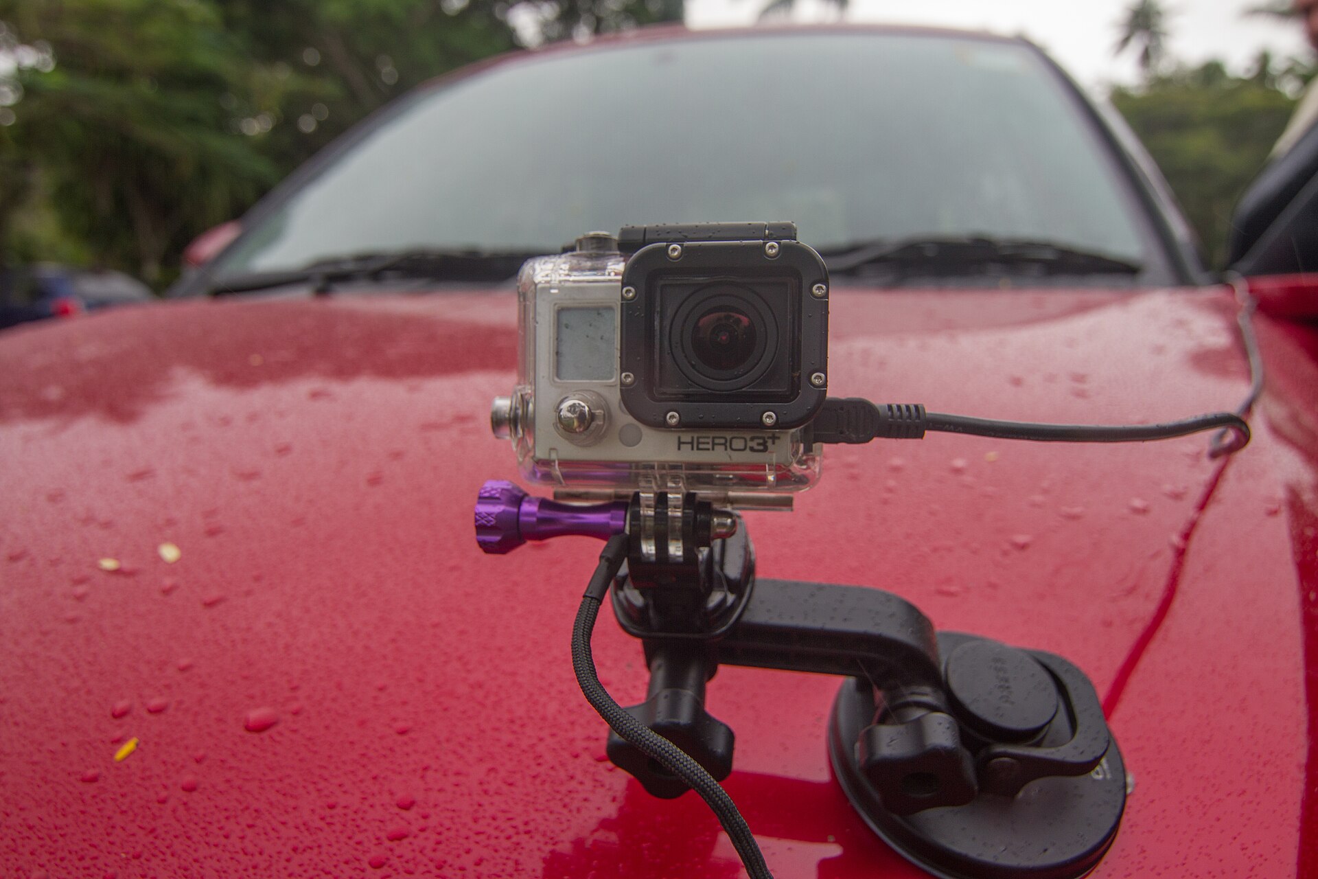 Action camera in a clear waterproof housing on a suction-cup mount on a car bonnet