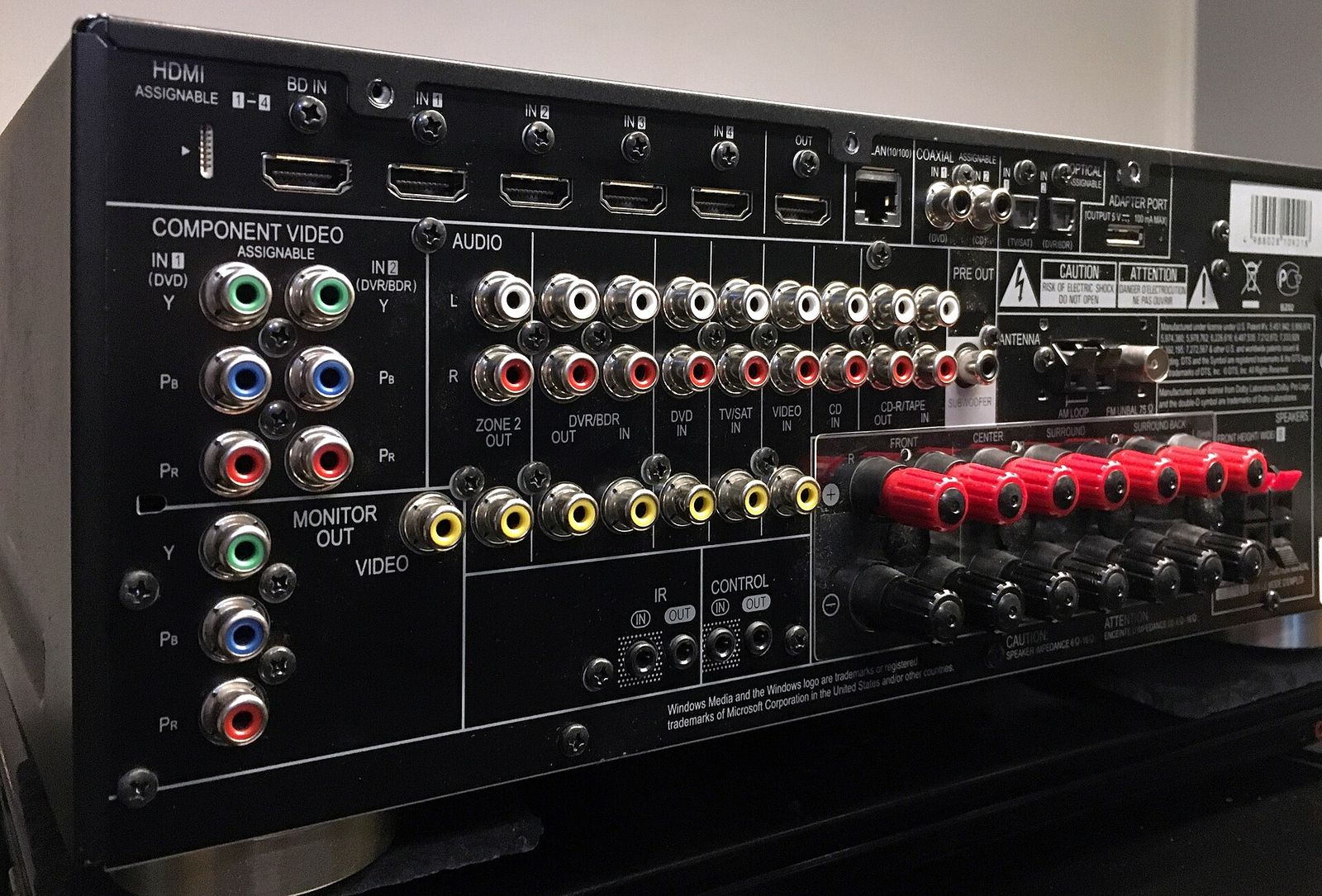 Rear panel of an AV receiver with rows of HDMI inputs and red and black speaker terminals