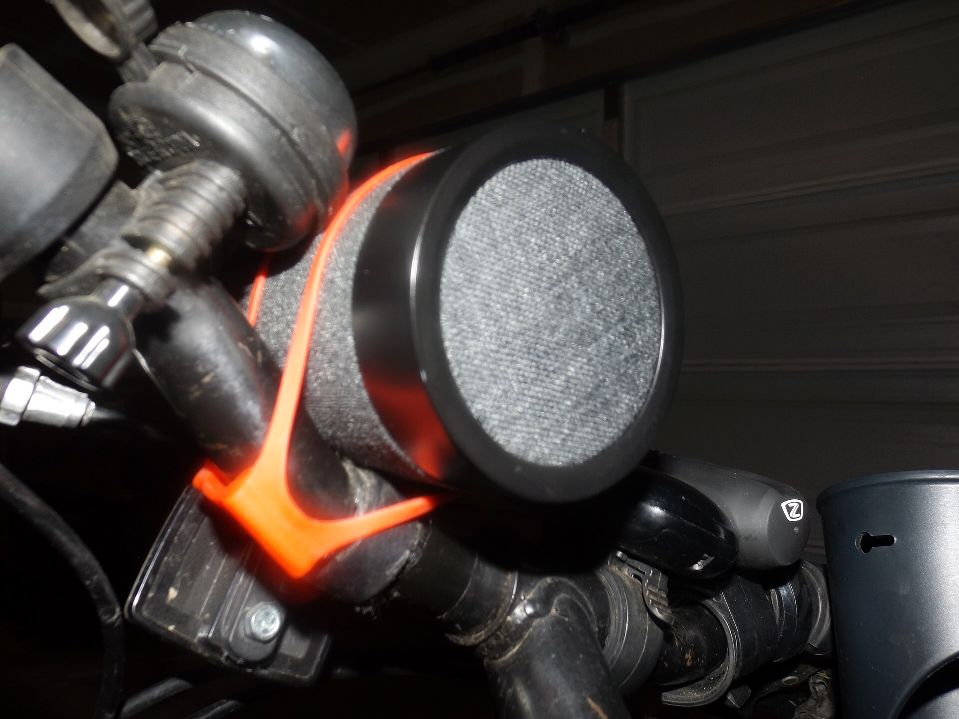 Small cylindrical wireless speaker with a fabric grille strapped to bicycle handlebars