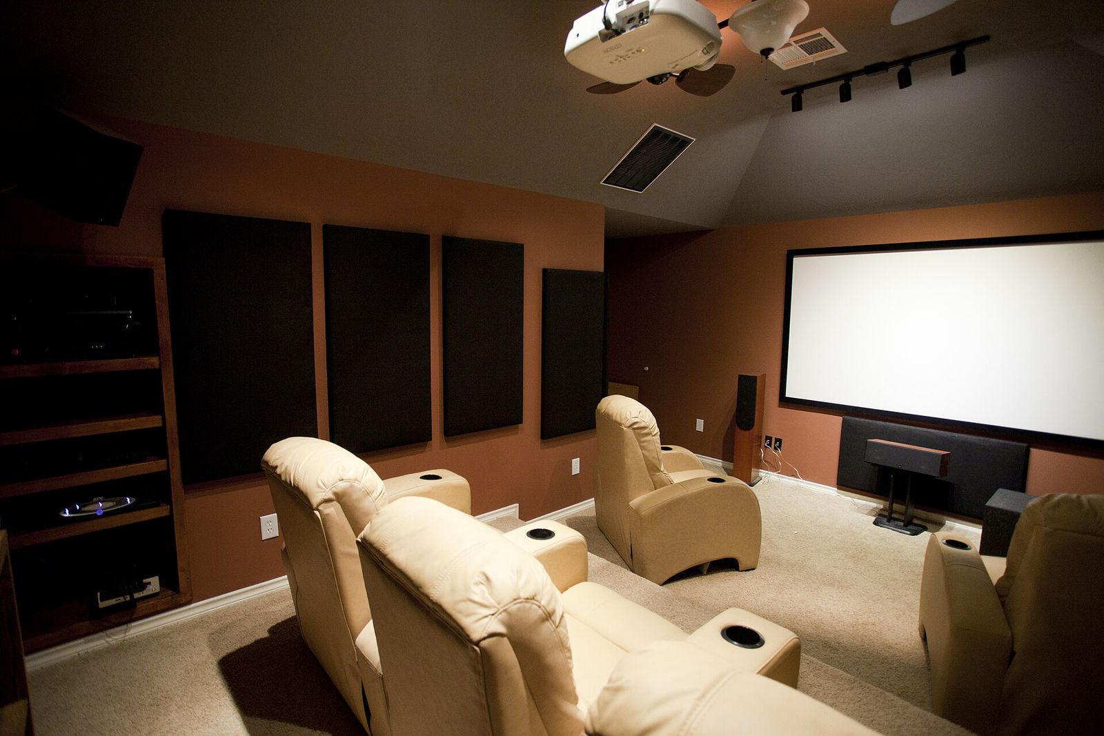 Home cinema room with a ceiling-mounted projector, large screen and reclining seats