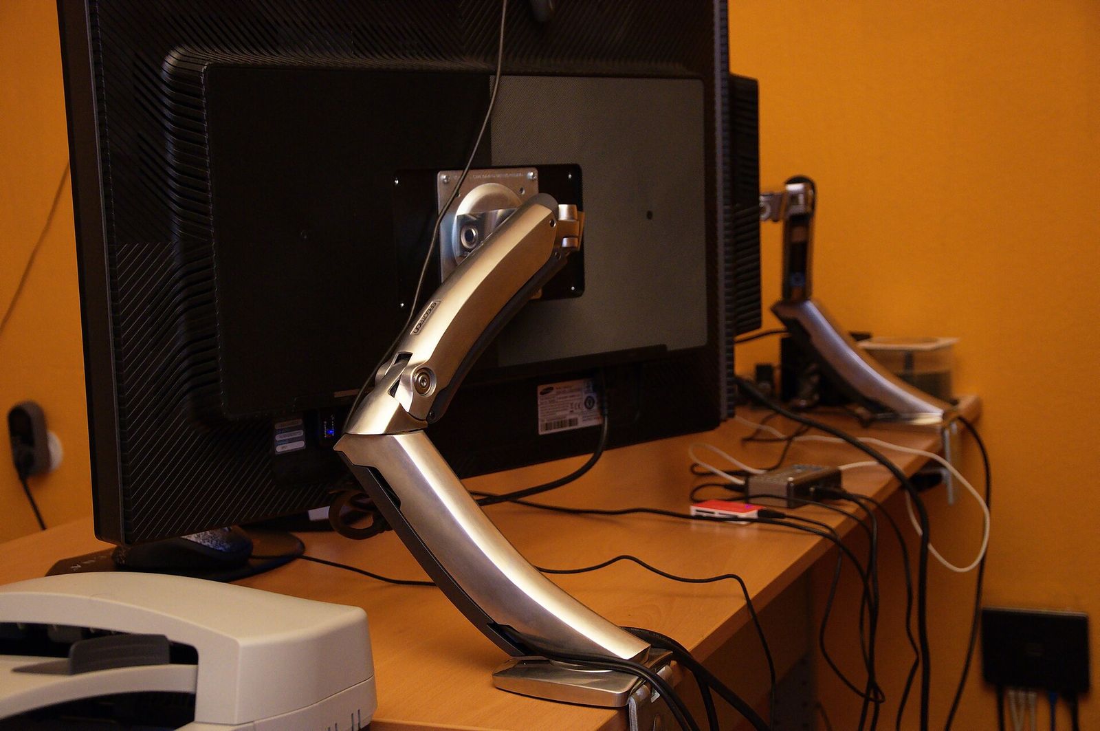 Computer monitors mounted on adjustable arms above a desk