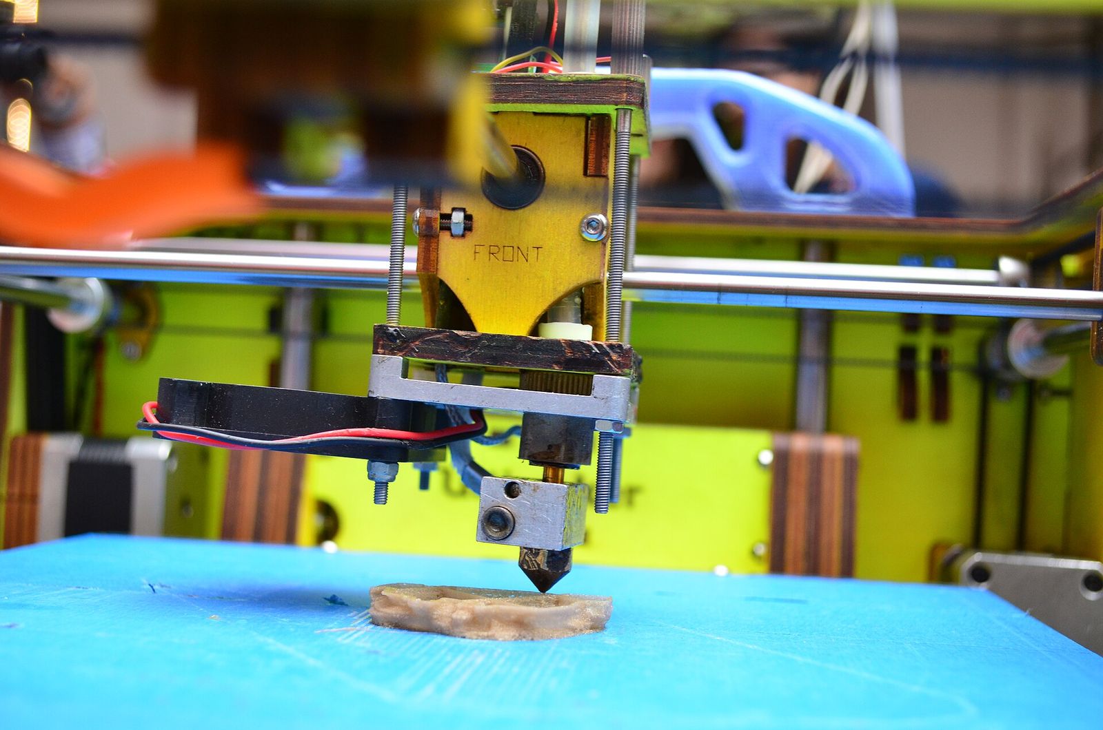 Close-up of an open-frame FDM 3D printer's nozzle laying down the first layers of a print