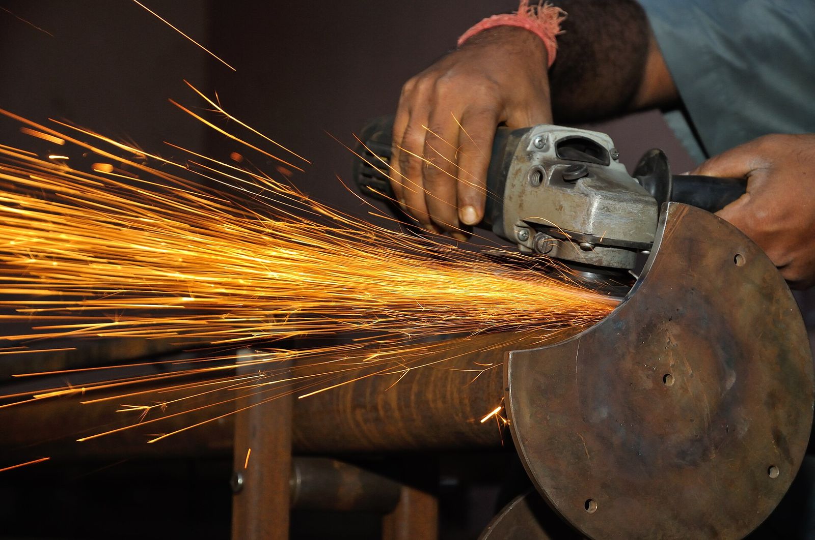 Sparks flying from an angle grinder working on a steel pipe