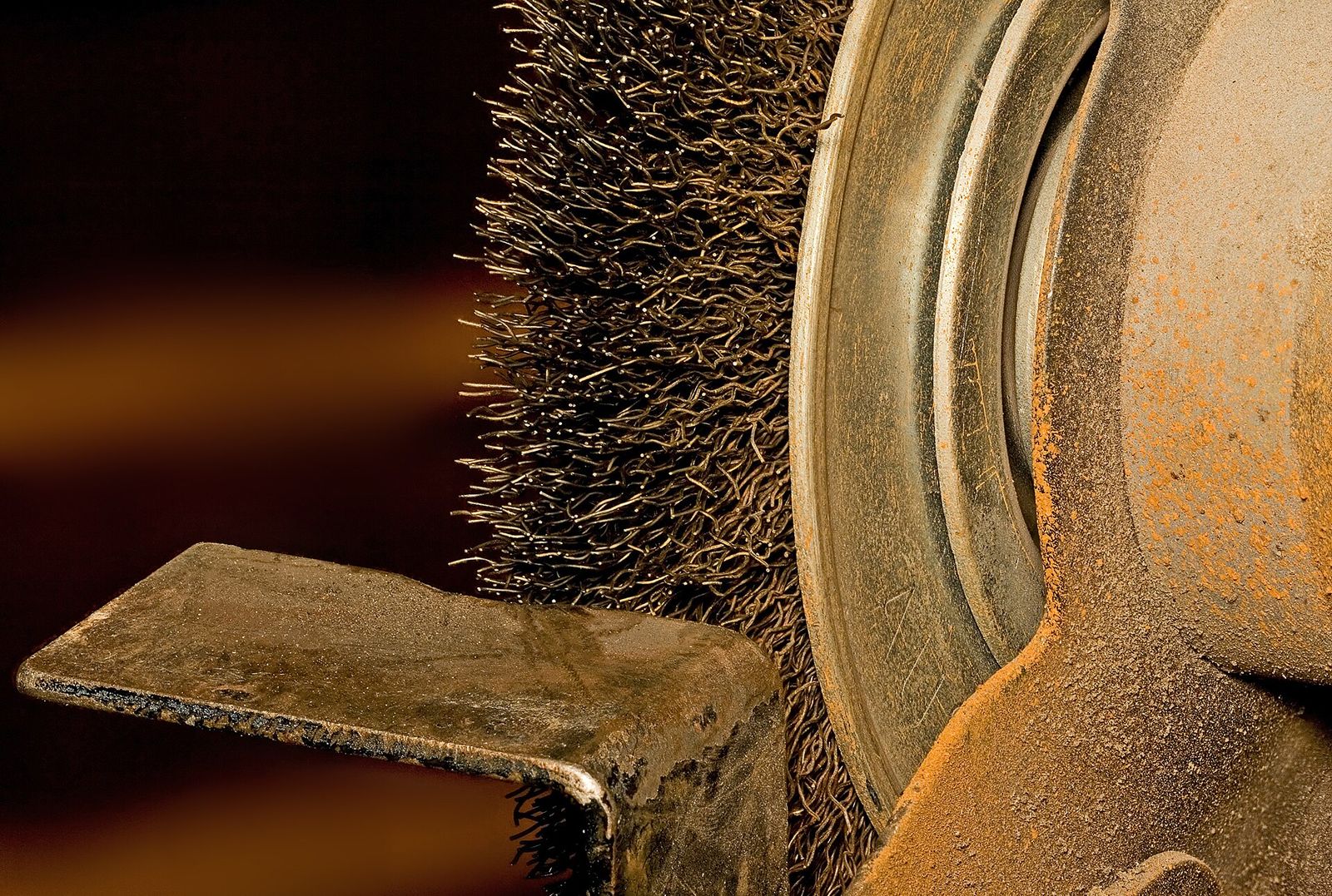 Close-up of a wire wheel and tool rest on an 8-inch bench grinder