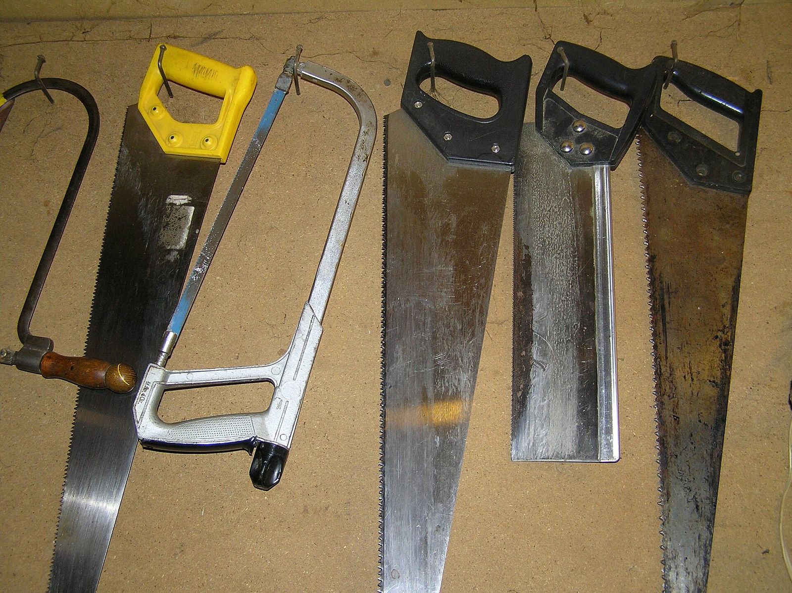 Panel saws, a backsaw and frame saws hanging on a workshop wall