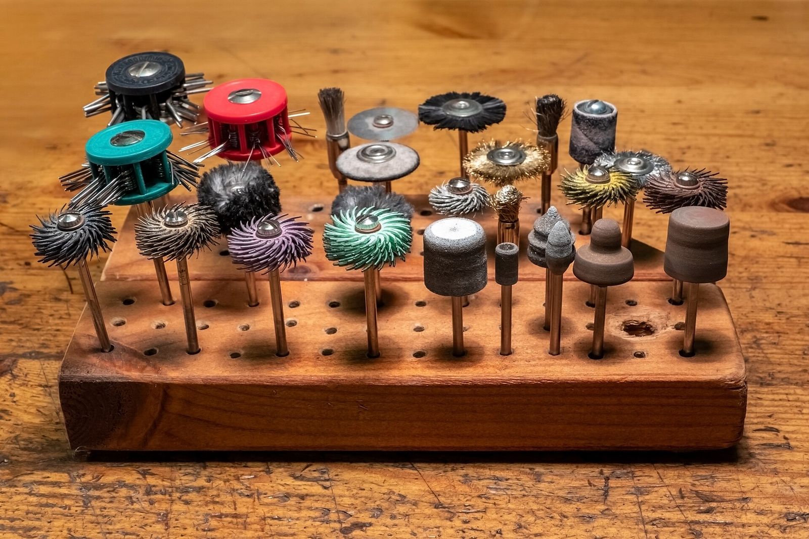 Rotary tool accessories, including brushes, sanding drums and grinding stones, in a wooden stand