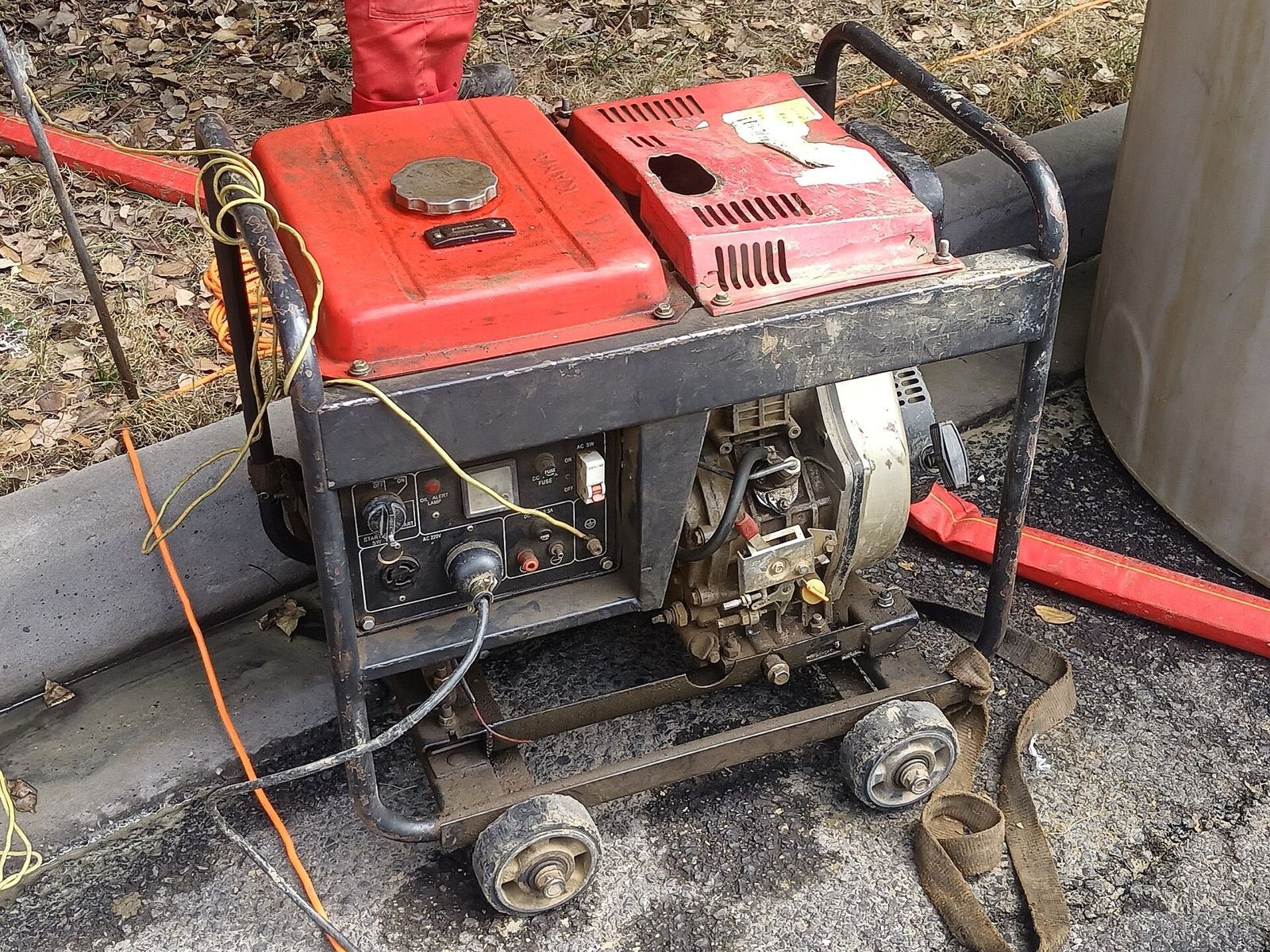 A well-used wheeled portable generator in a steel frame, parked outdoors on a work site