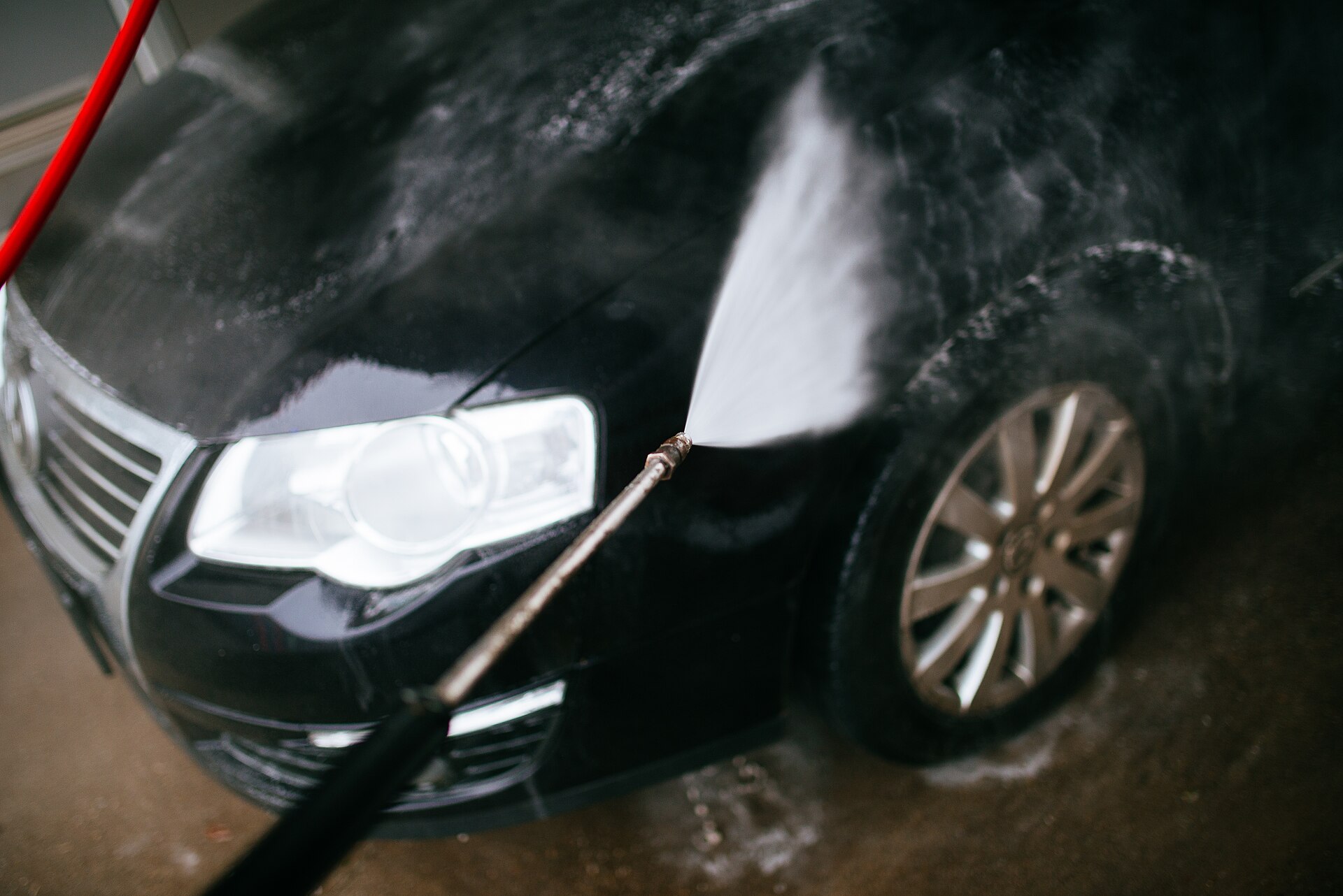 A pressure washer jet spraying a black car