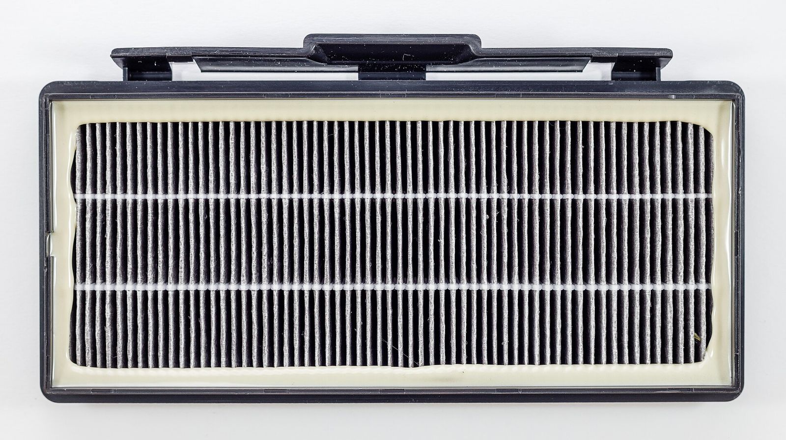 A used pleated vacuum filter clogged with fine dust
