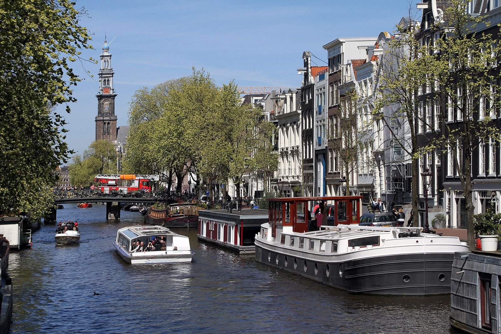 Boats and houseboats on the Prinsengracht canal with the Westerkerk tower behind