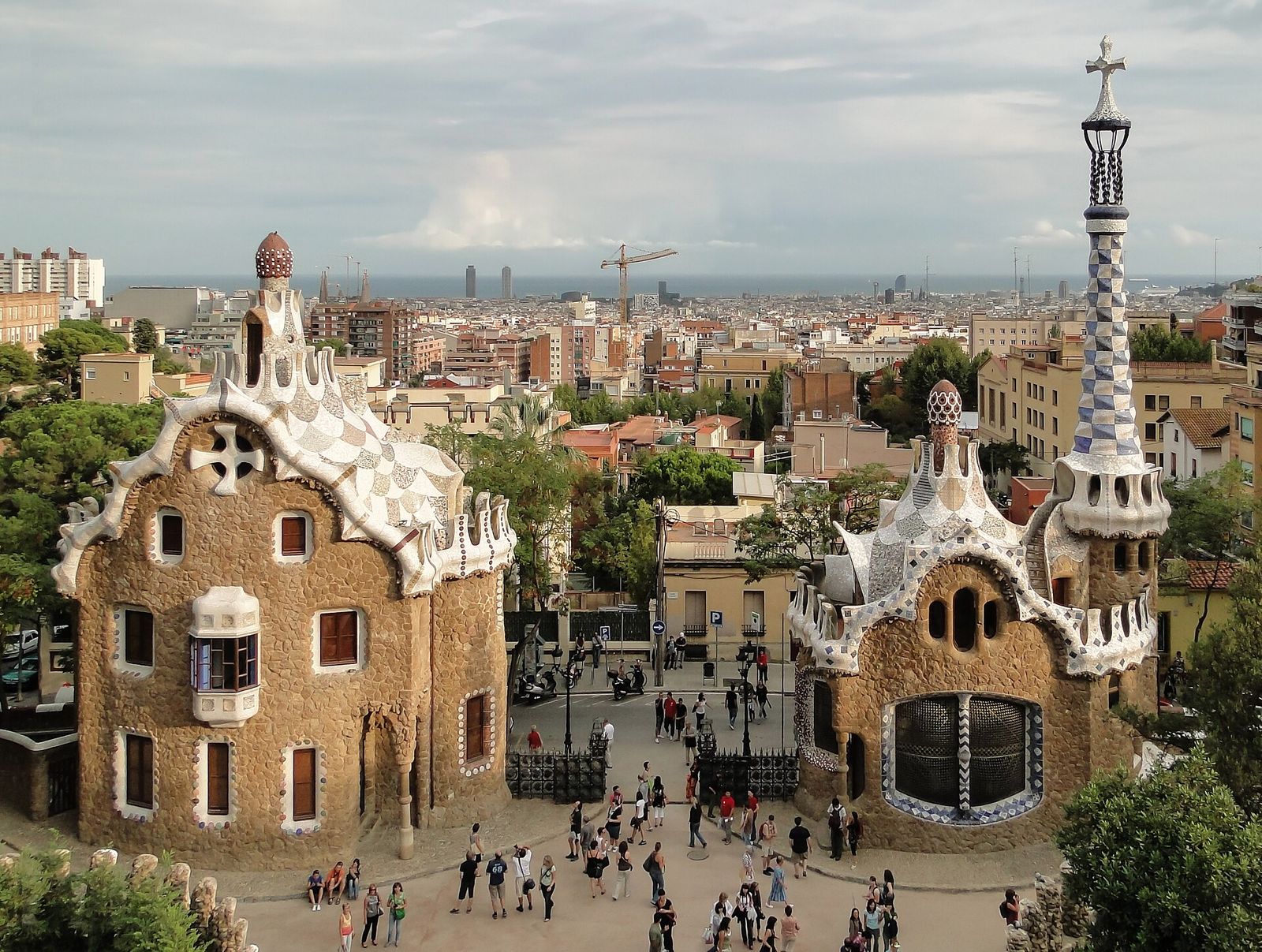 Gaudí's mosaic-roofed gatehouses at the entrance to Park Güell, with Barcelona stretching to the sea