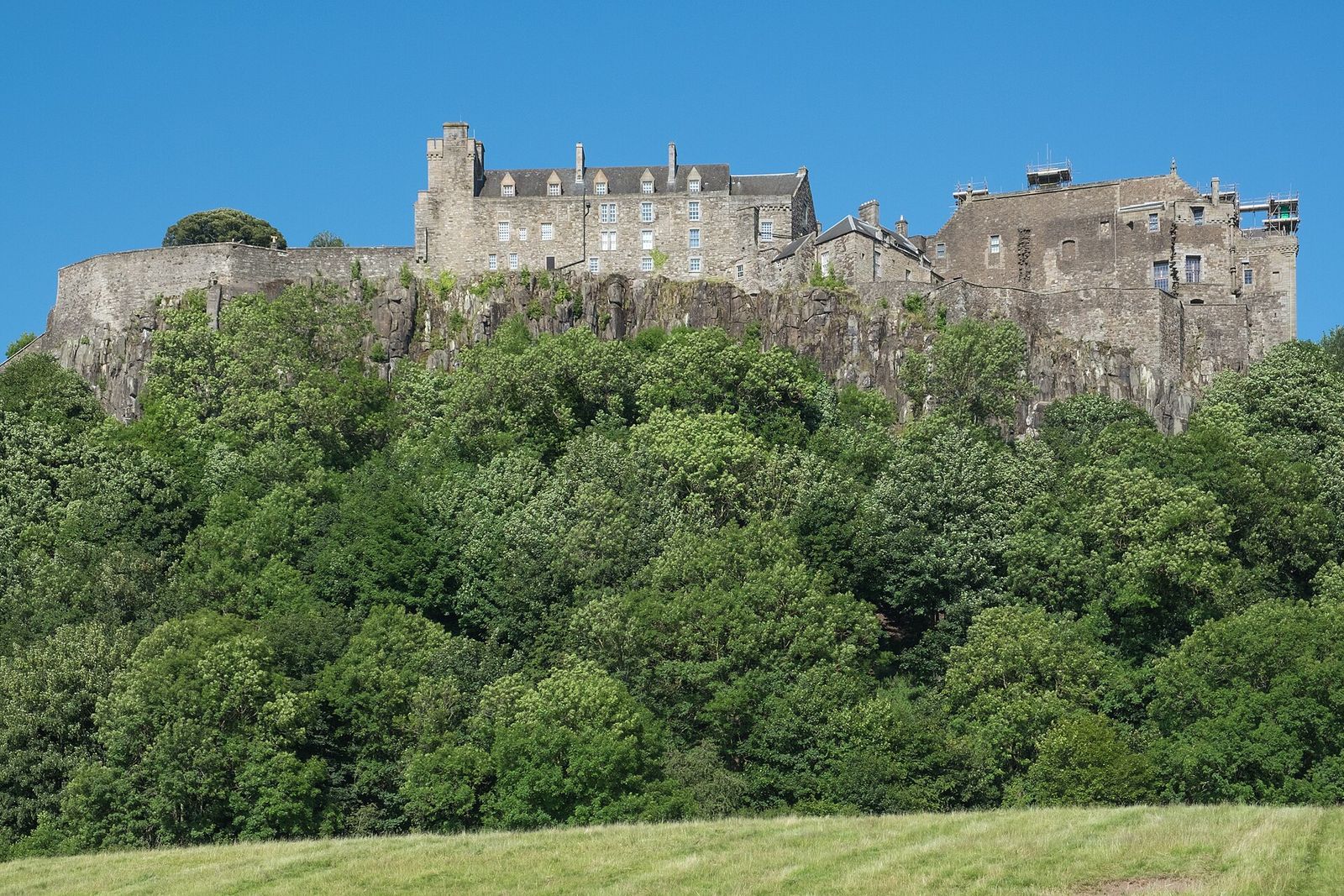 Stirling Castle on its volcanic crag above wooded slopes on a clear summer day
