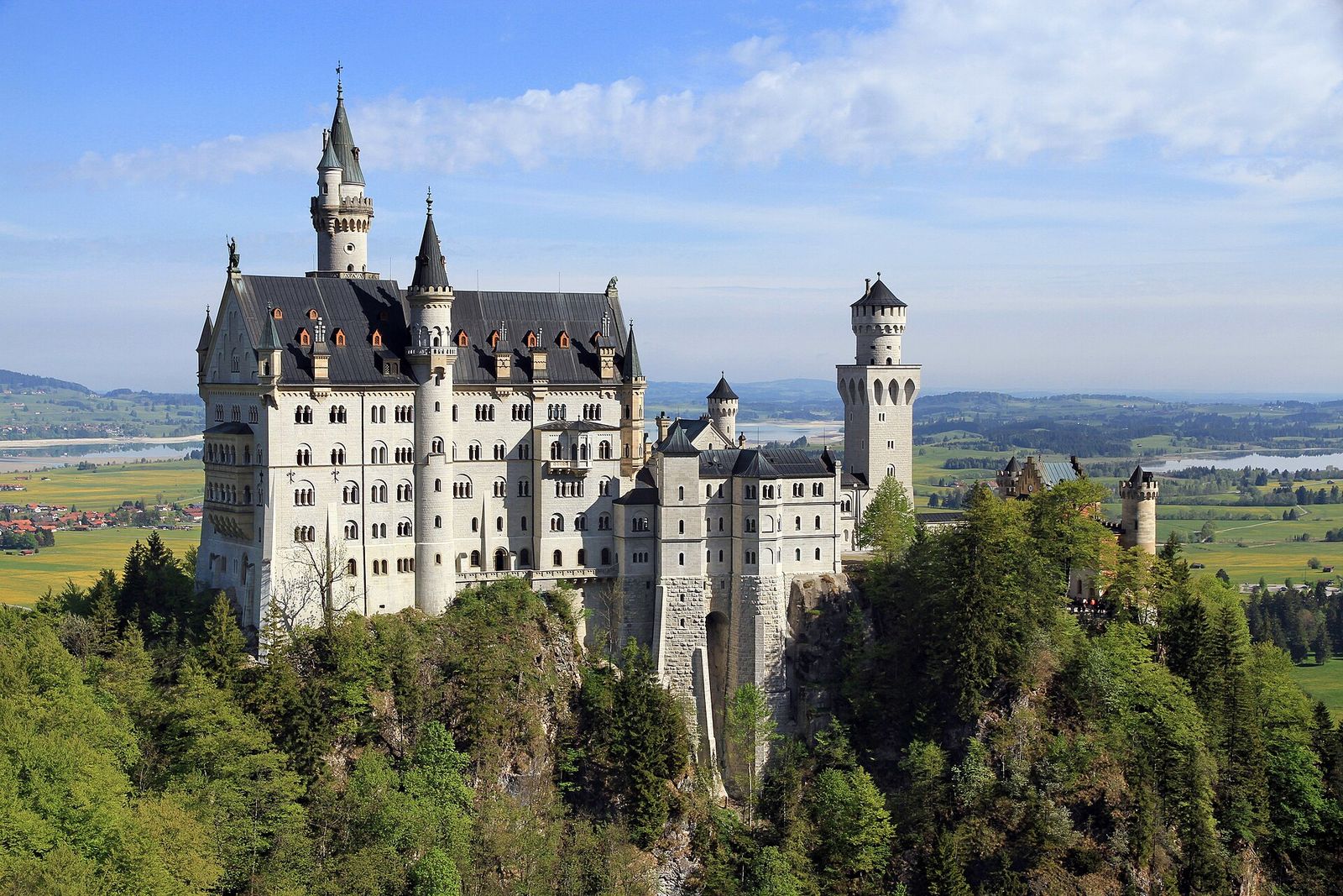 Neuschwanstein Castle on its wooded crag above the Bavarian countryside, seen from the Marienbrücke