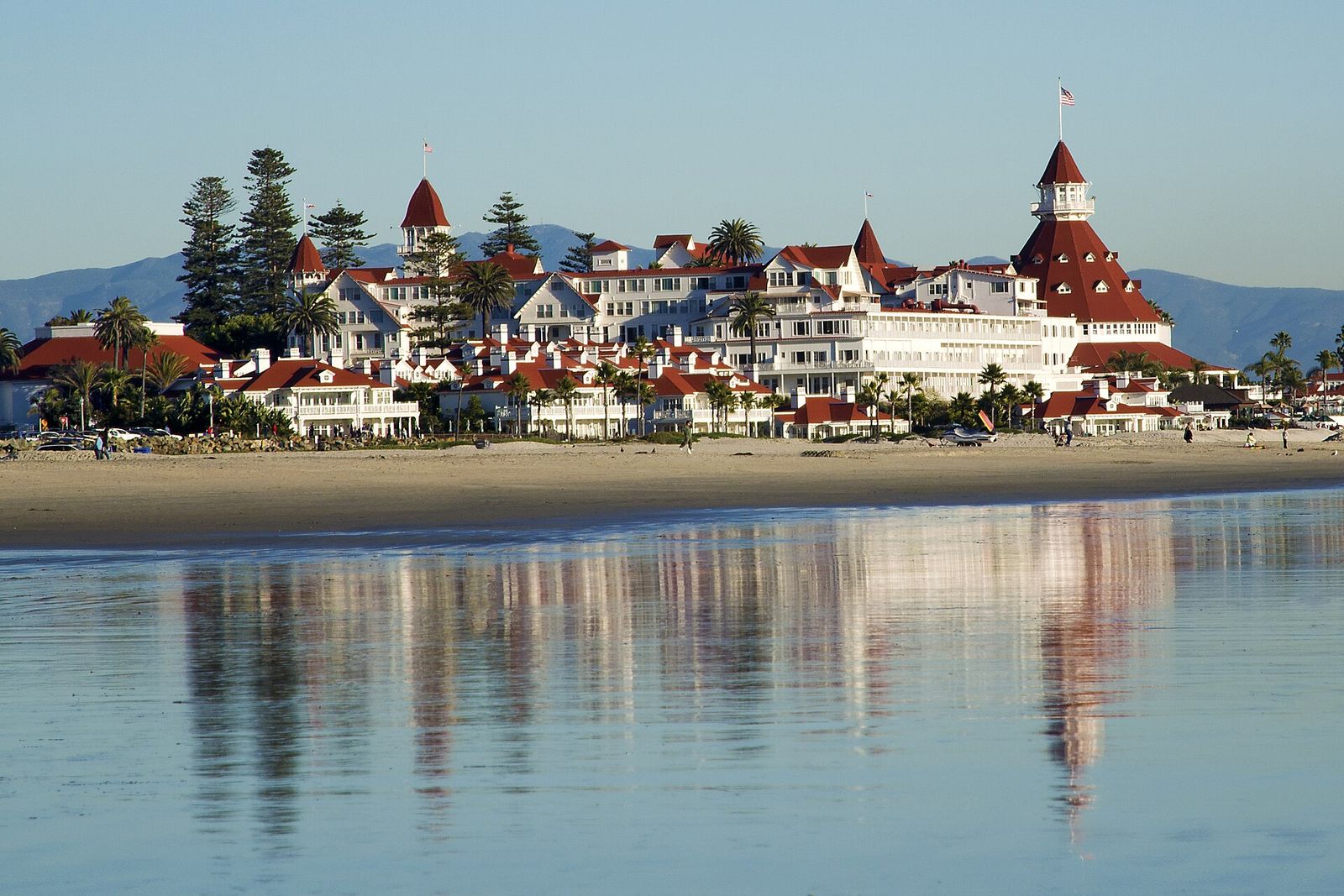 The white wings and red turrets of the Hotel del Coronado seen from the beach