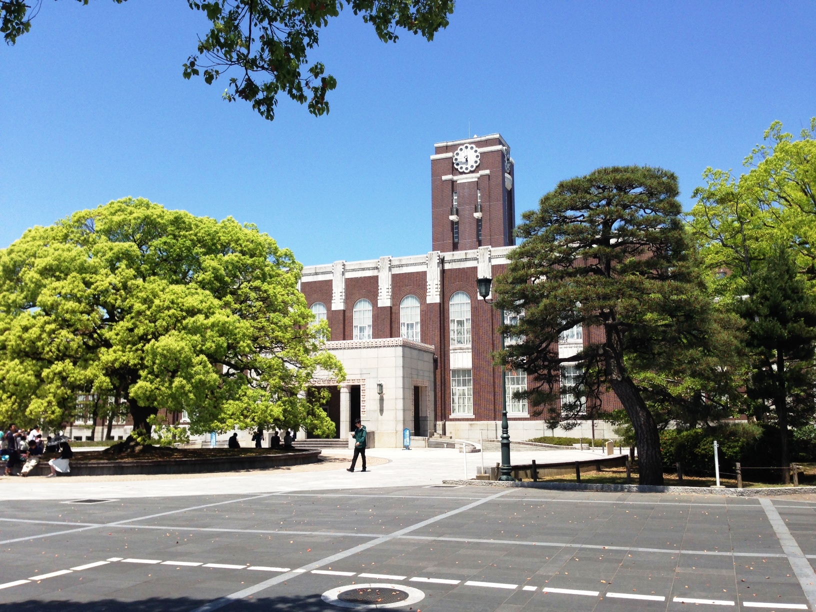 The brick clock tower of Kyoto University's Yoshida campus behind a large camphor tree