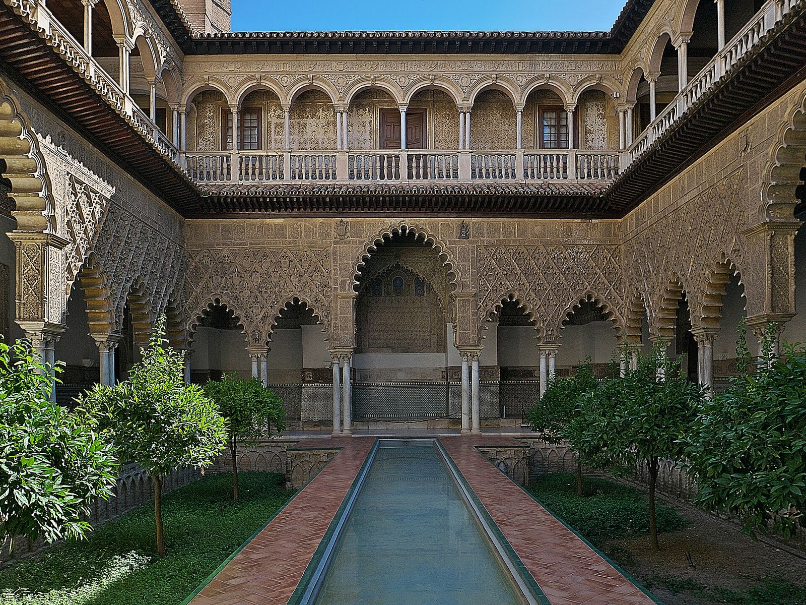 The Patio de las Doncellas in the Real Alcázar of Seville, with carved arches around a long sunken pool