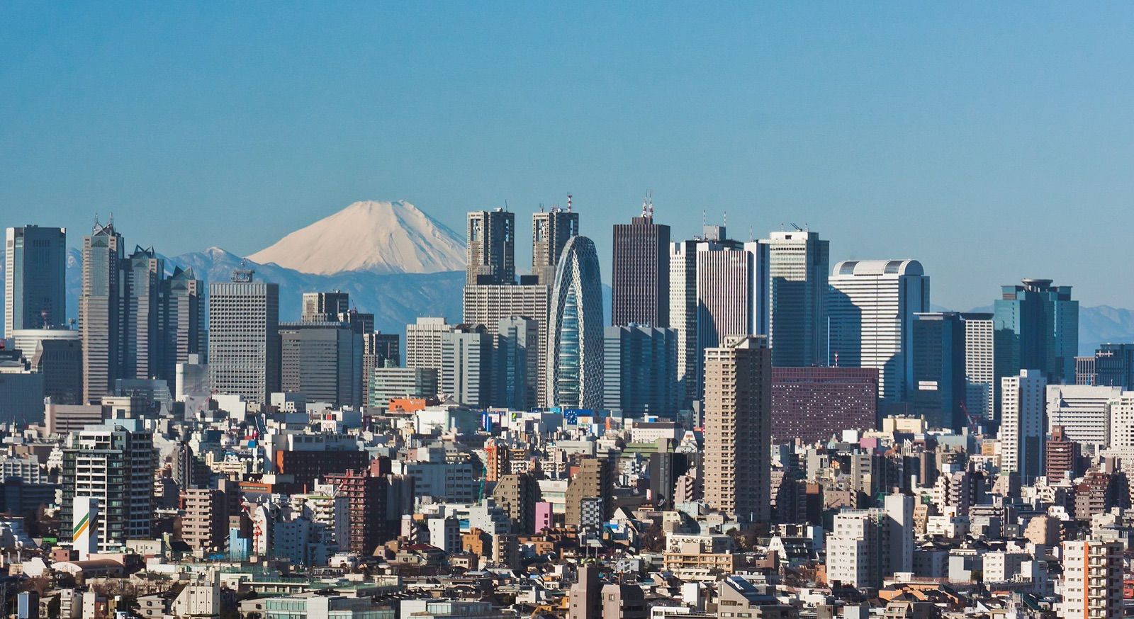 The skyscrapers of west Shinjuku in Tokyo with snow-capped Mount Fuji in the distance