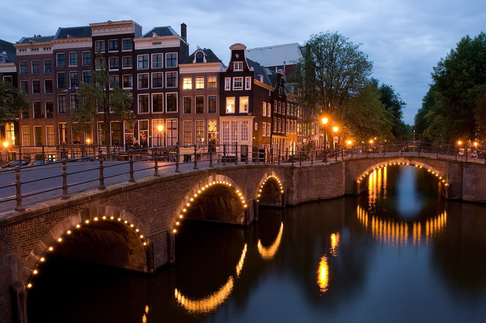 Lit bridges where the Keizersgracht meets the Reguliersgracht in Amsterdam at dusk