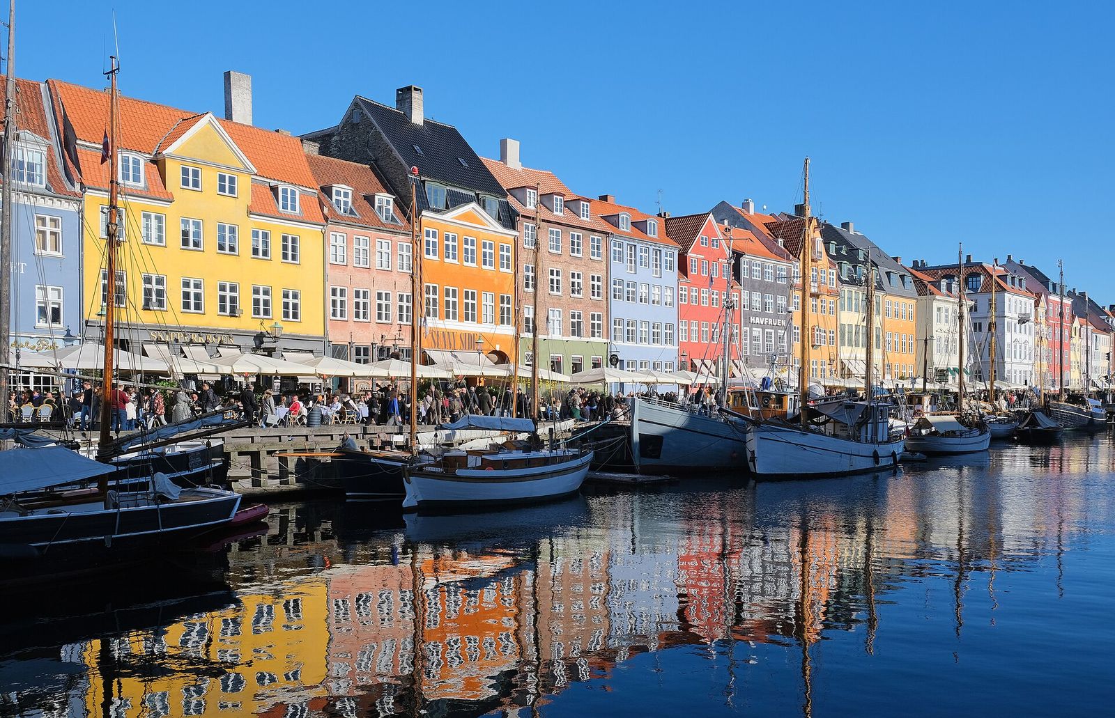 Colourful gabled townhouses and wooden sailing boats along the Nyhavn canal in Copenhagen