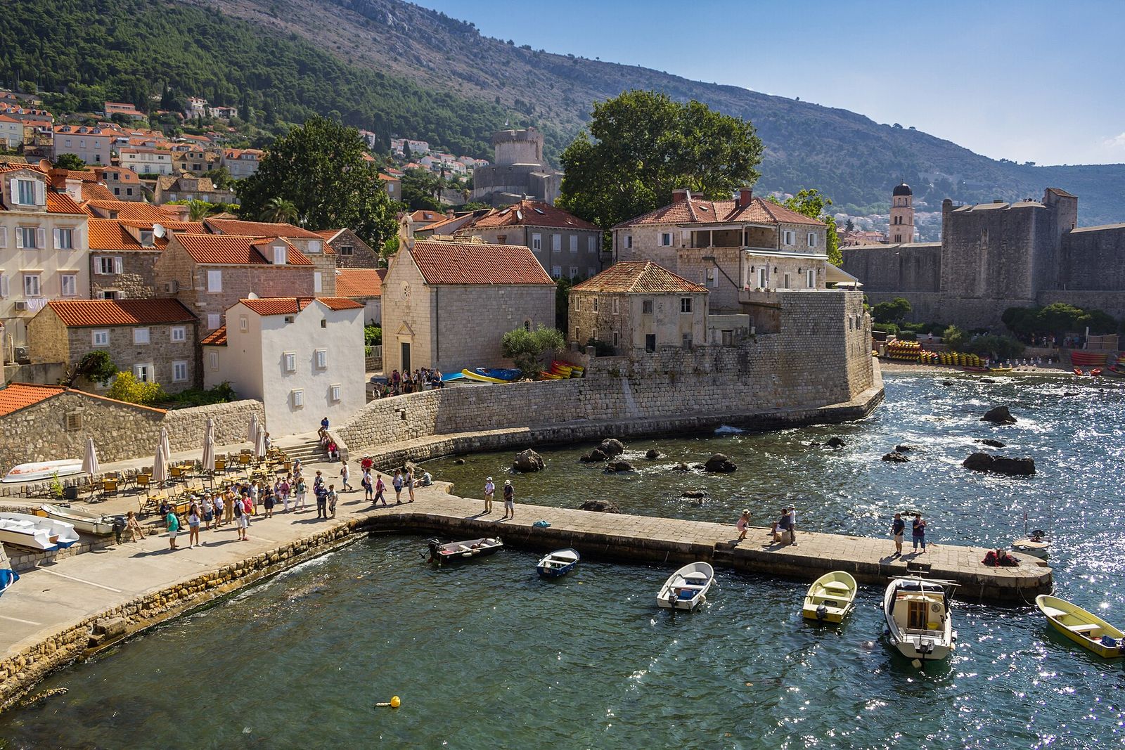 Dubrovnik's old harbour beneath the stone city walls, with the Minčeta Tower and the slopes of Mount Srđ behind