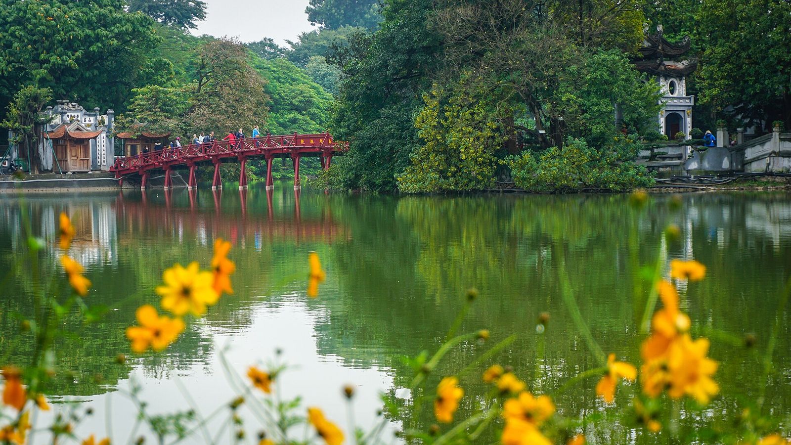 The red Huc Bridge reflected in the green water of Hoan Kiem Lake in central Hanoi