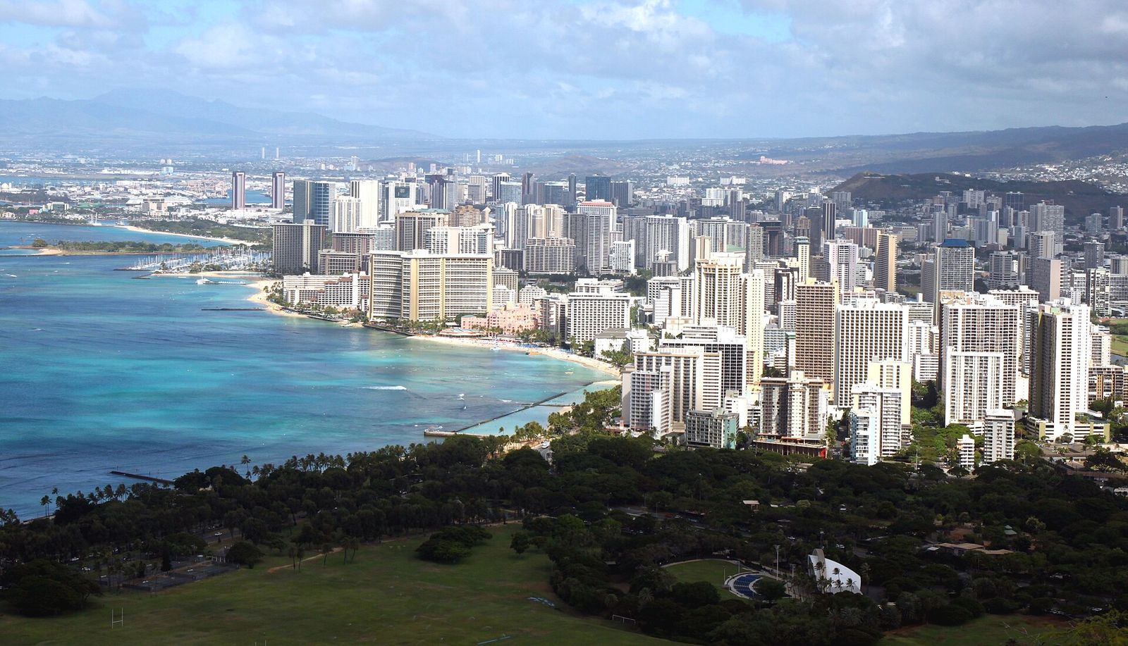 Waikiki's hotel towers and beach curving along the shore, seen from the rim of Diamond Head