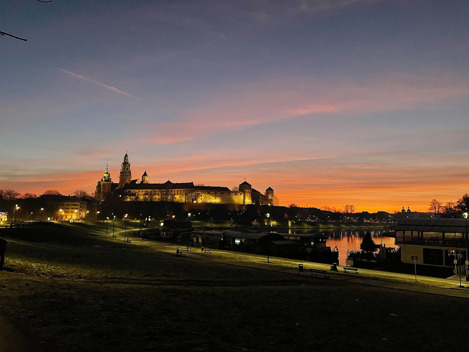 Wawel Castle and Cathedral lit up at dawn above the Vistula river in Kraków