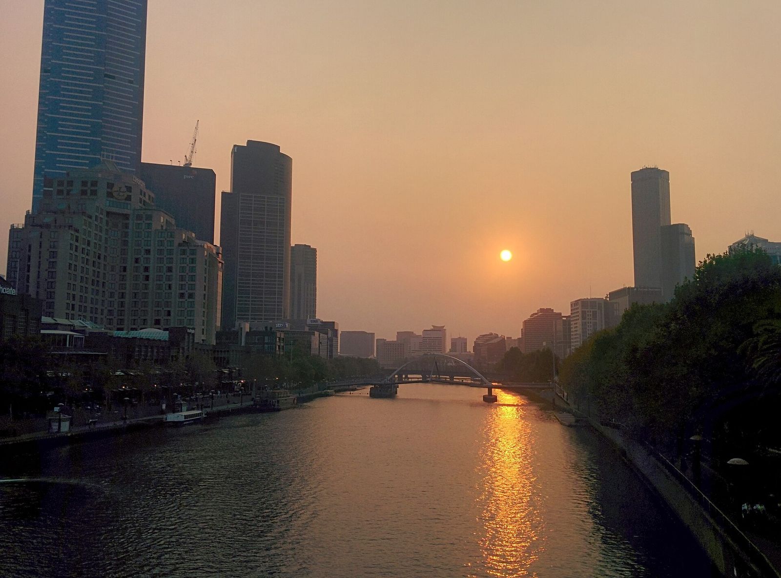 The Yarra River at sunset between the Melbourne city centre and Southbank, with a footbridge across the river